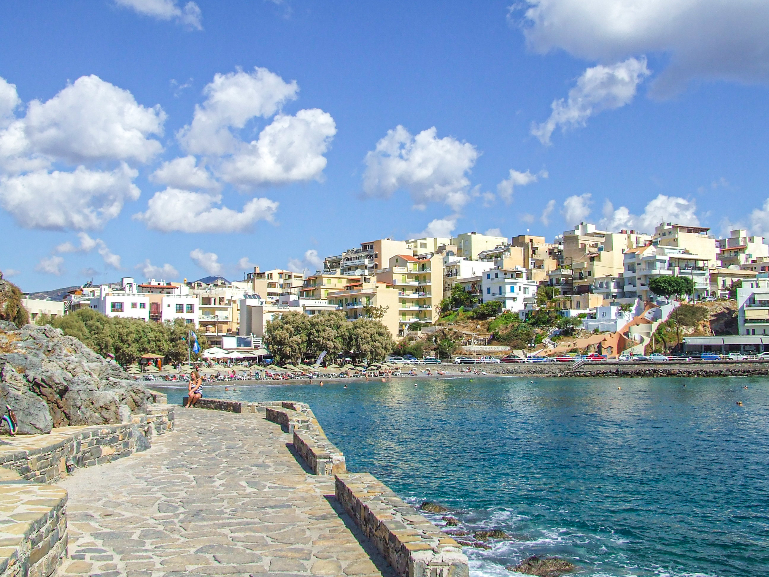 coastal town with a rocky pier extending into clear blue waters
