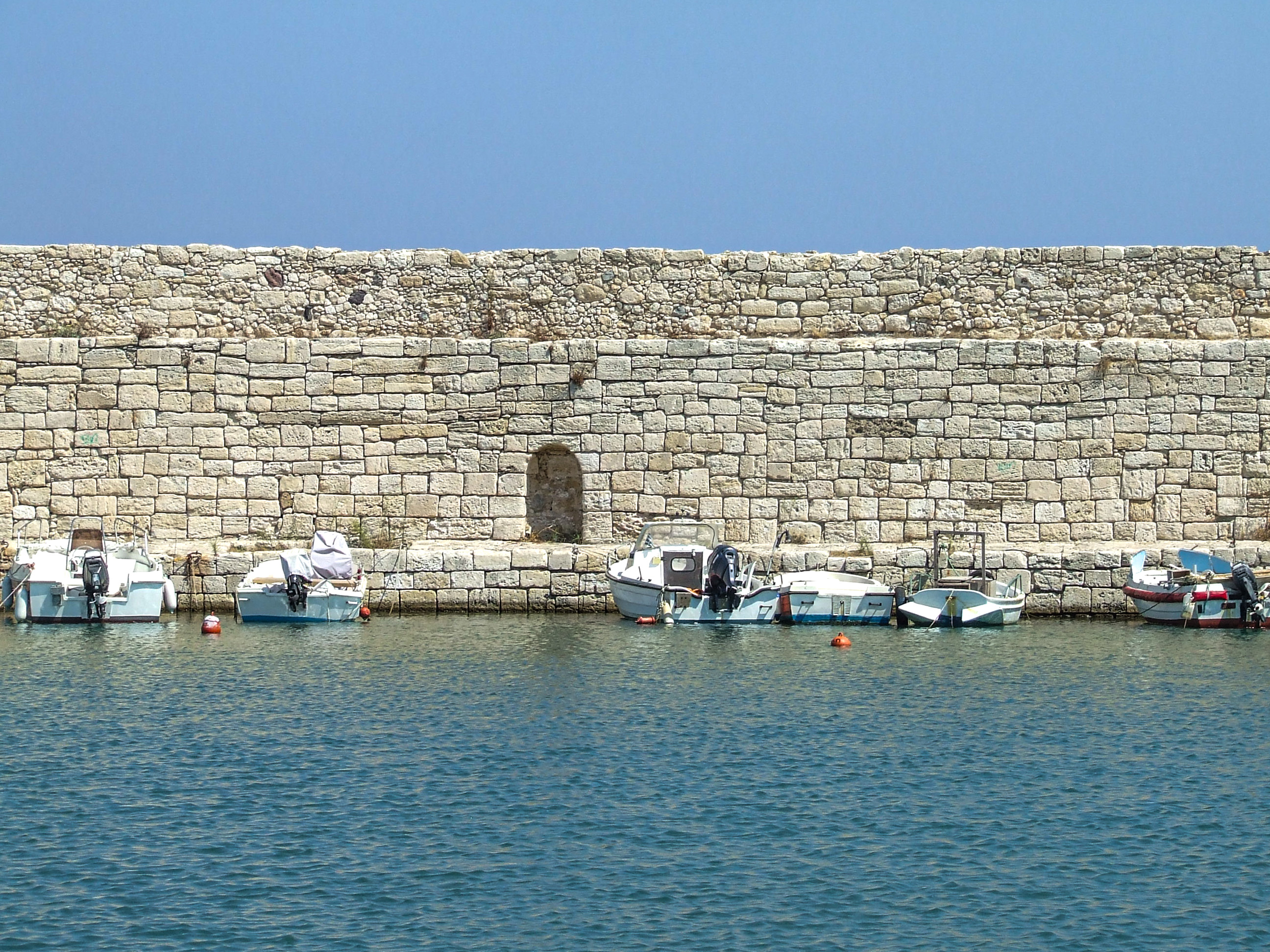 small boats docked against a stone wall