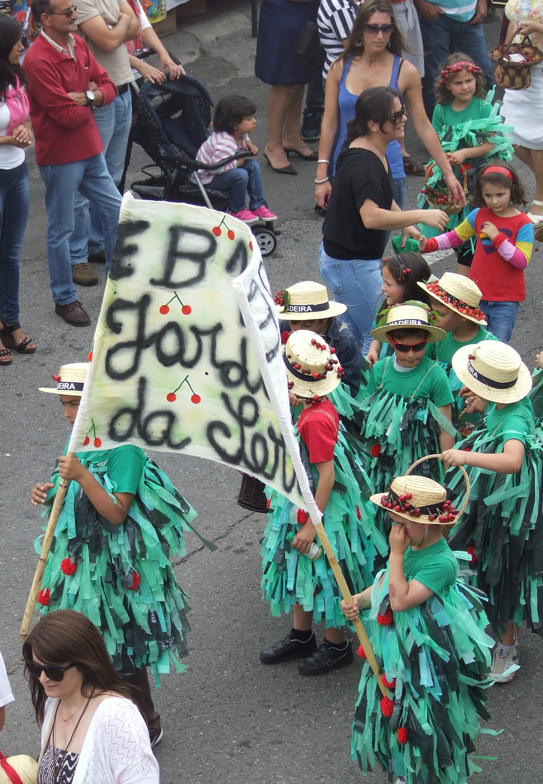 children dressed in green outfits and straw hats adorned with cherries