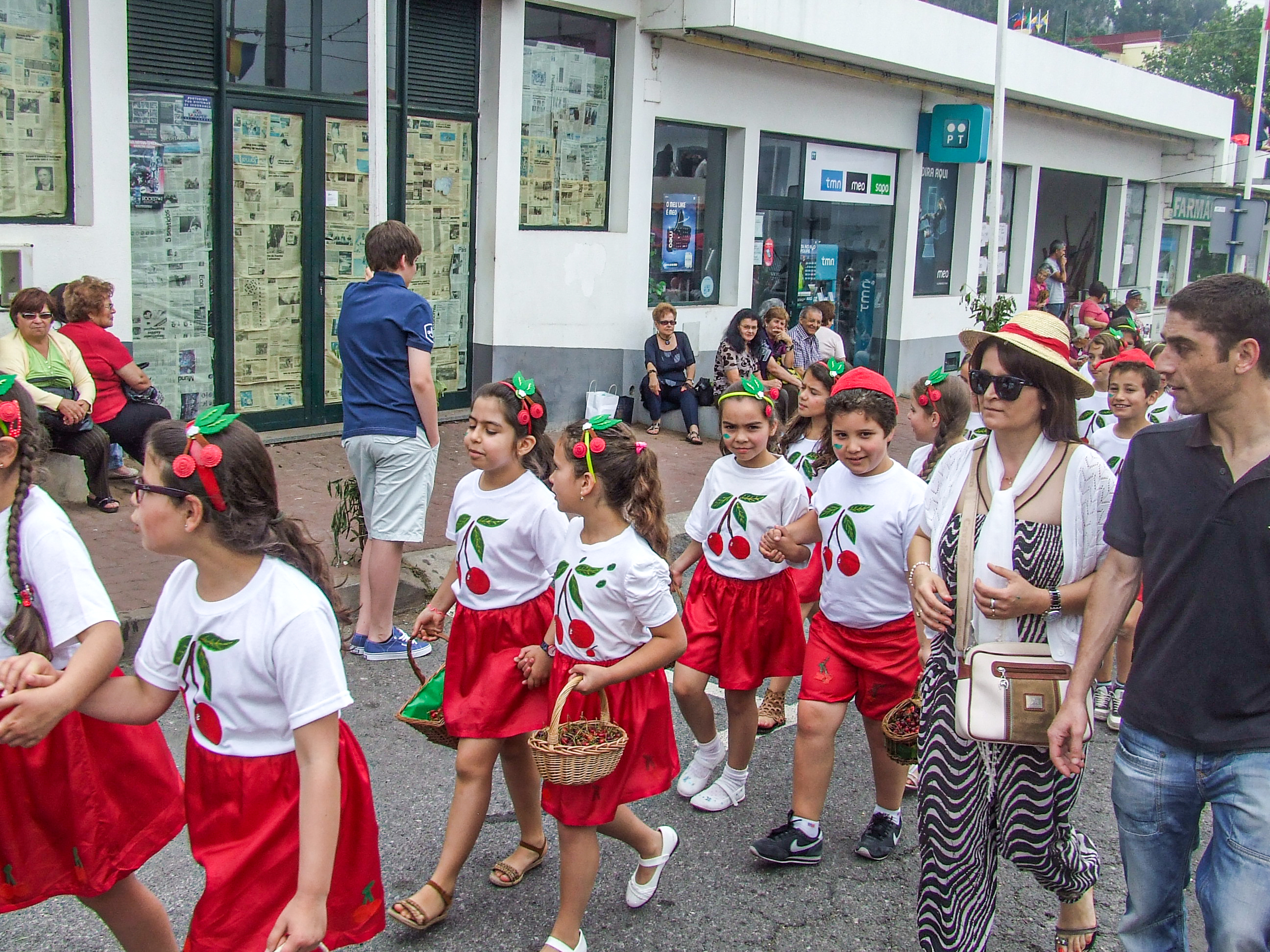 a group of children dressed in matching outfits, consisting of white T-shirts with cherry designs
