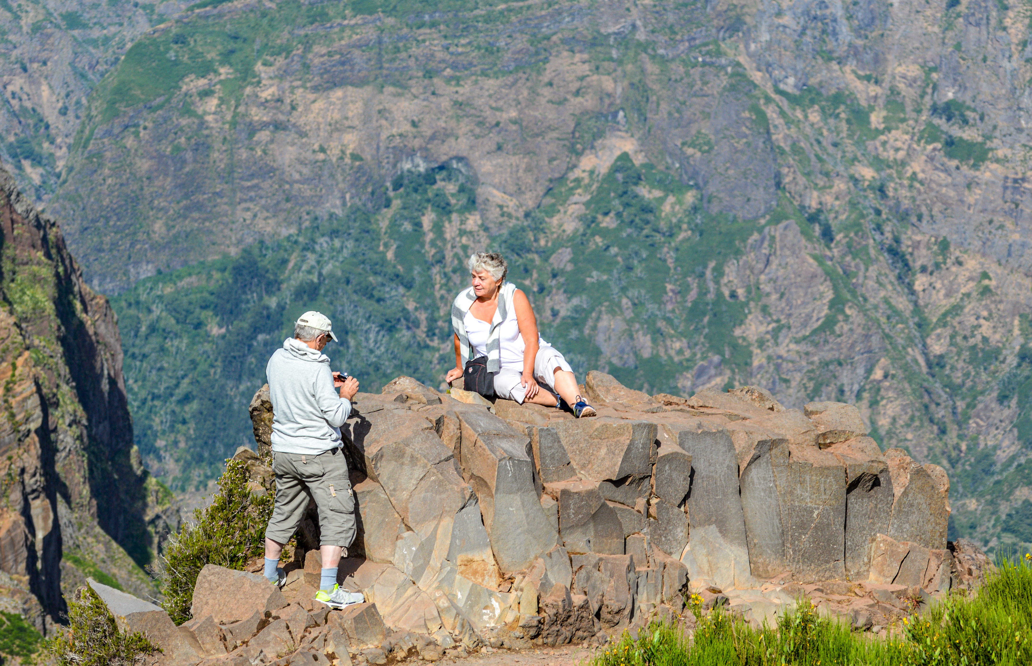 two individuals enjoying a scenic viewpoint in a mountainous area
