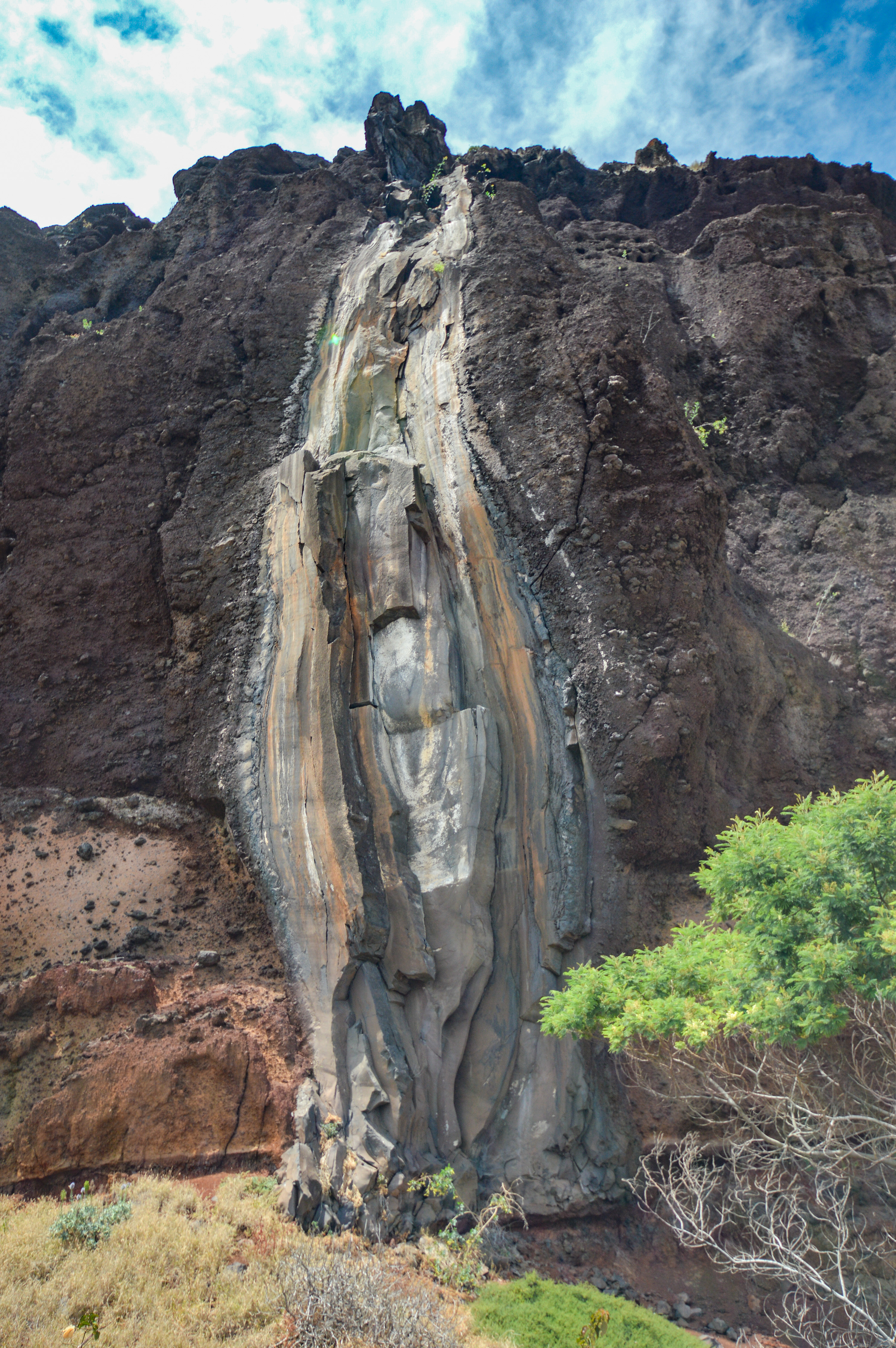 rocky cliff with a prominent vertical streak of lighter-colored rock running down its center