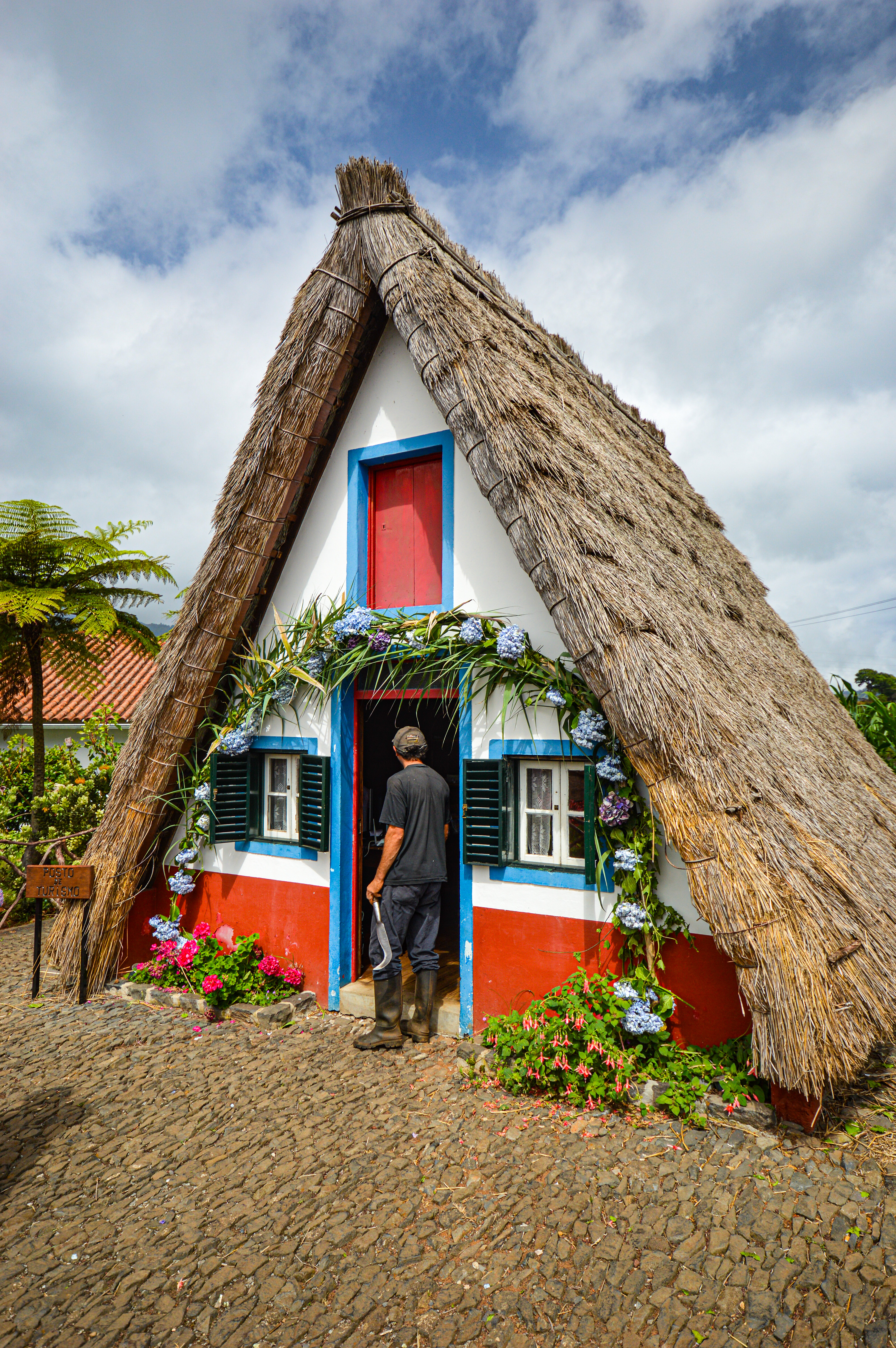 traditional thatched-roof house with a man standing at the entrance