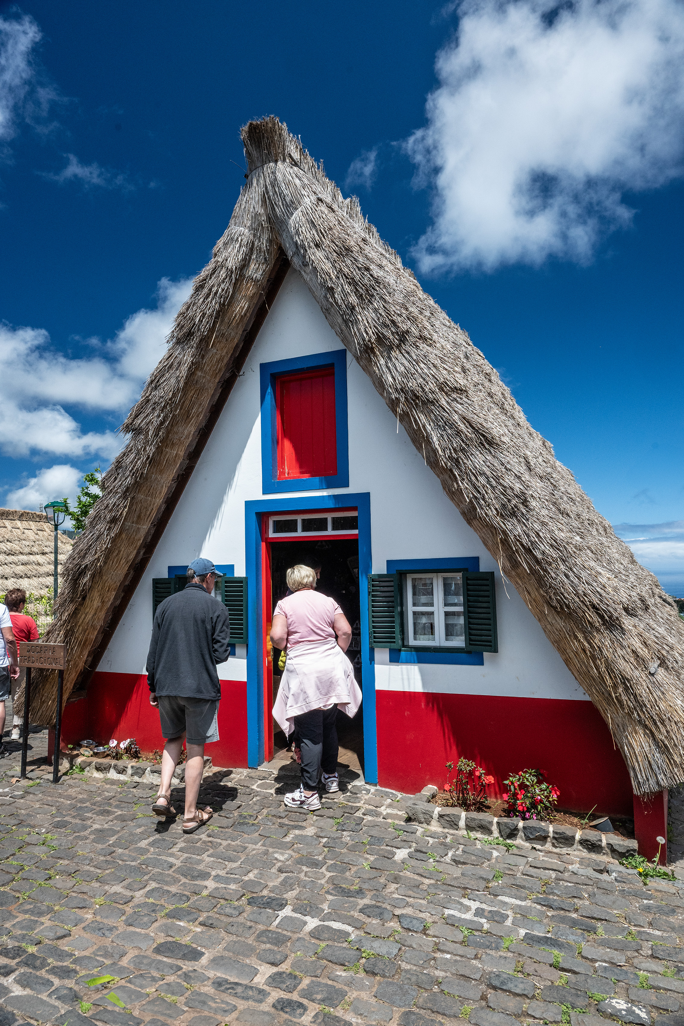 traditional thatched-roof house with a vibrant red and white exterior