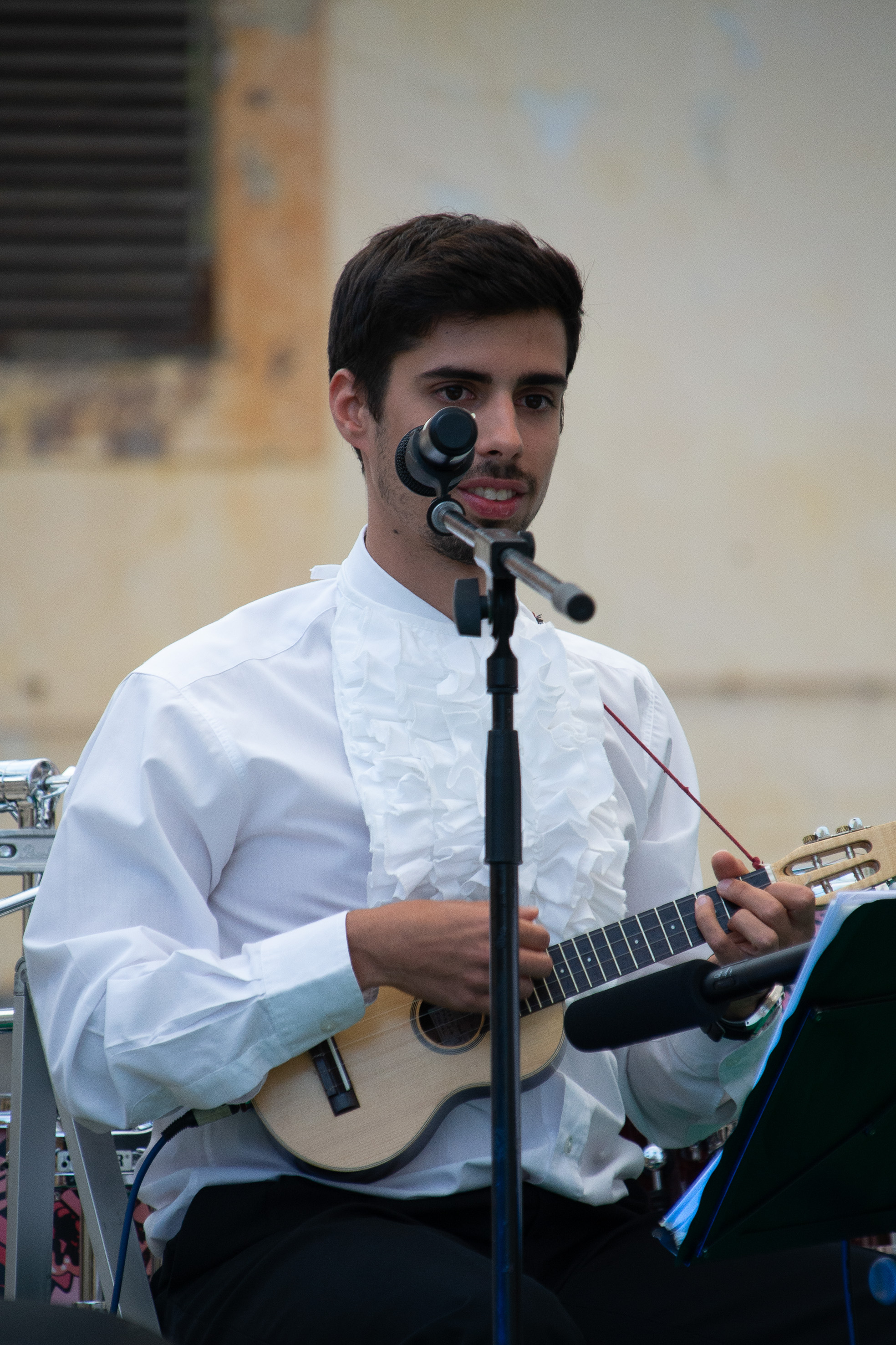 playing a ukulele and singing into a microphone