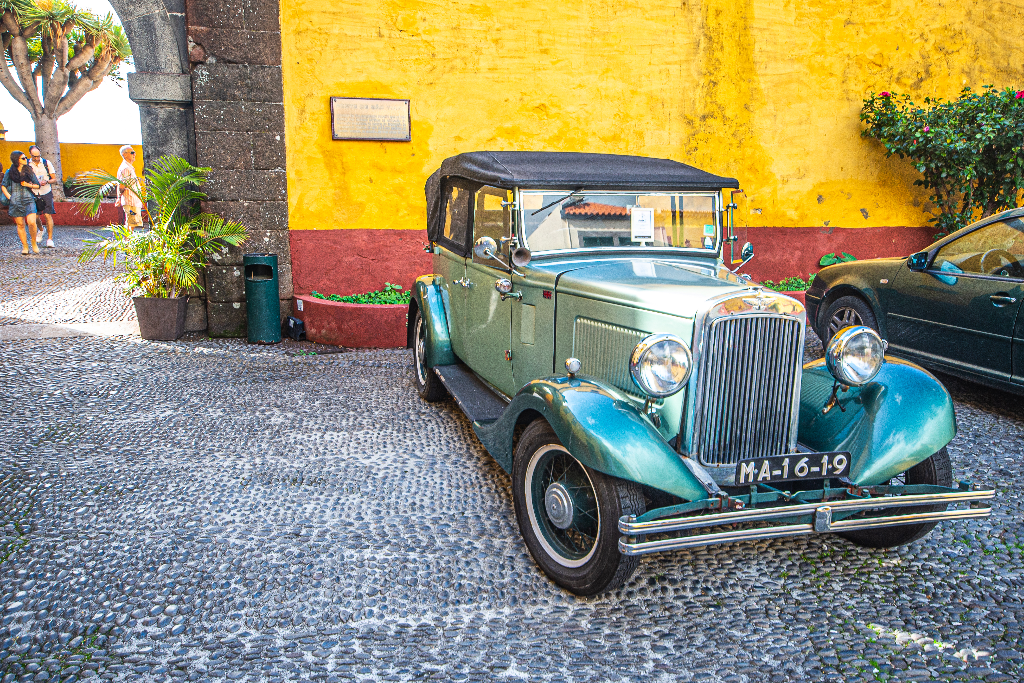 a vintage car parked on a cobblestone street