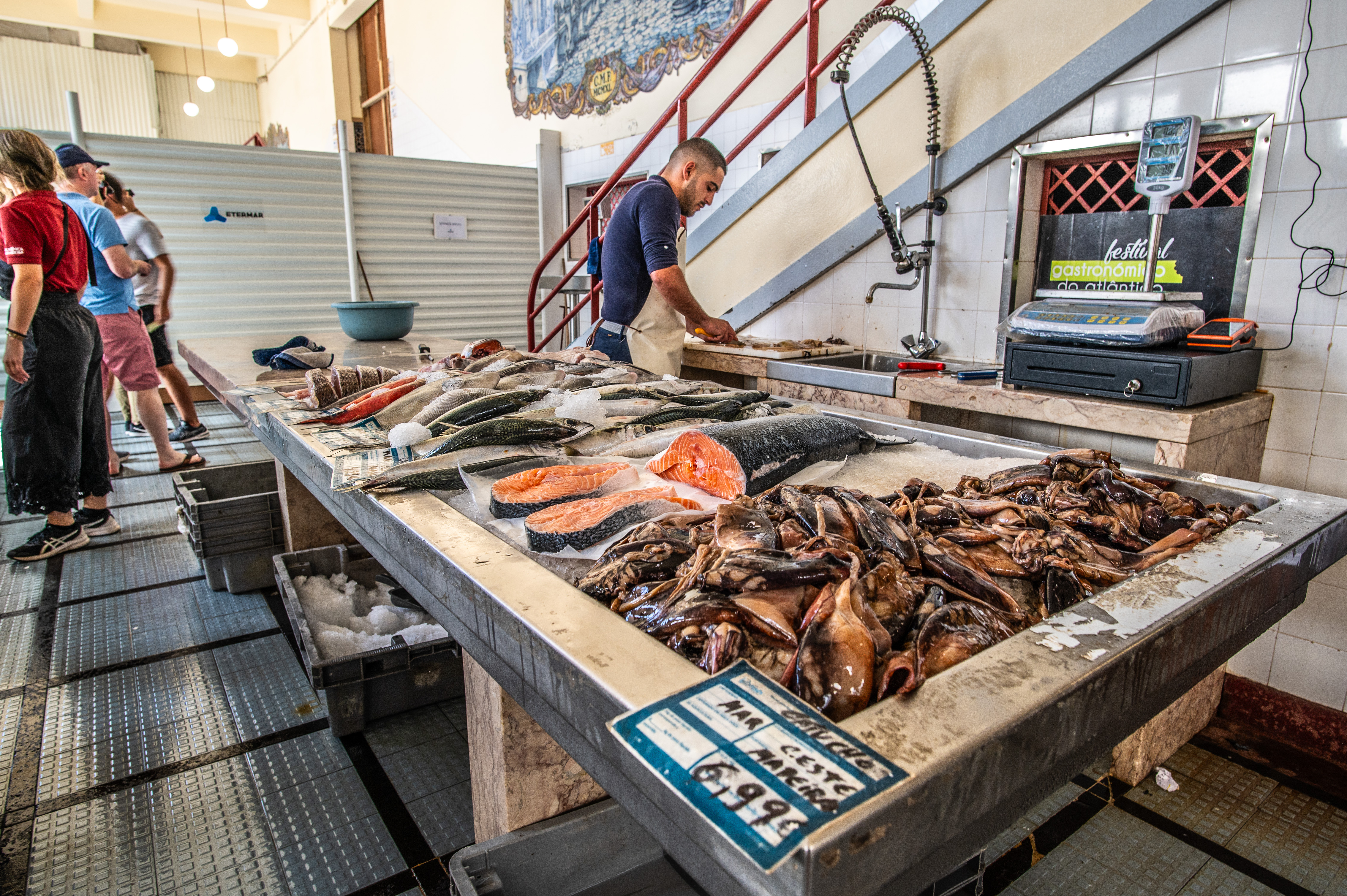 A fishmonger is seen attending to a counter laden with a variety of fresh seafood