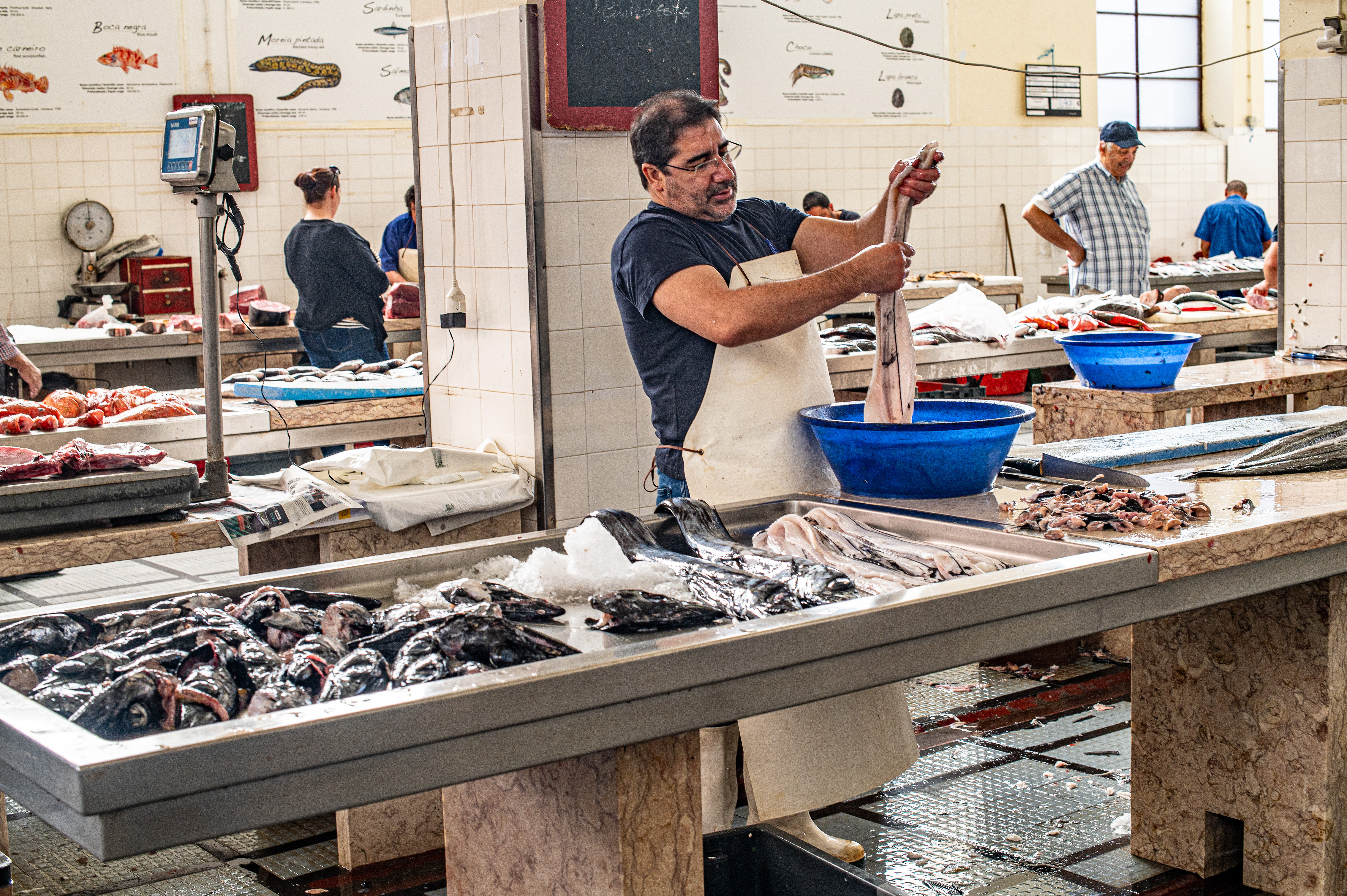 One vendor in the foreground is cleaning a fish