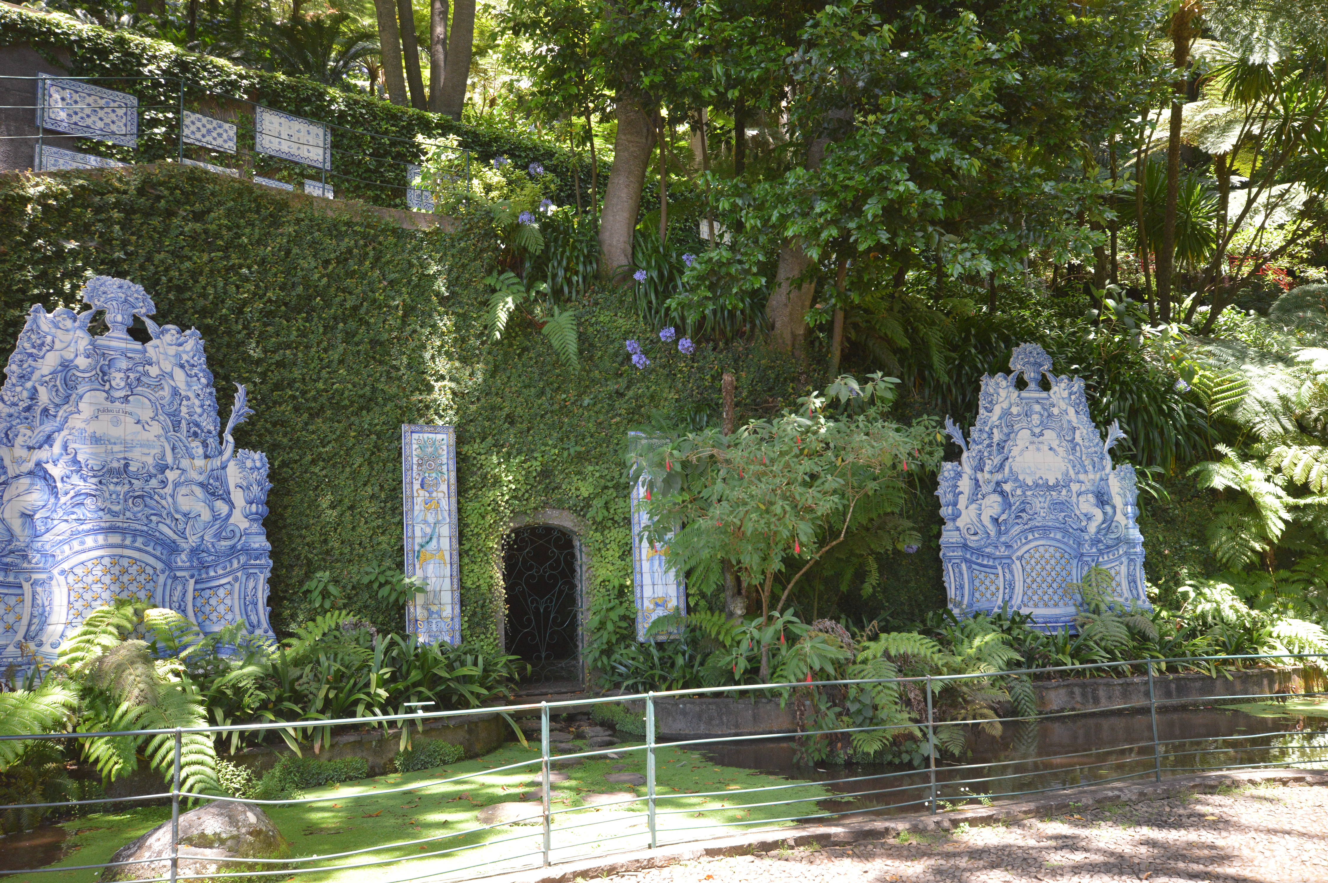 green garden with a small, ornate structure covered in blue and white tiles