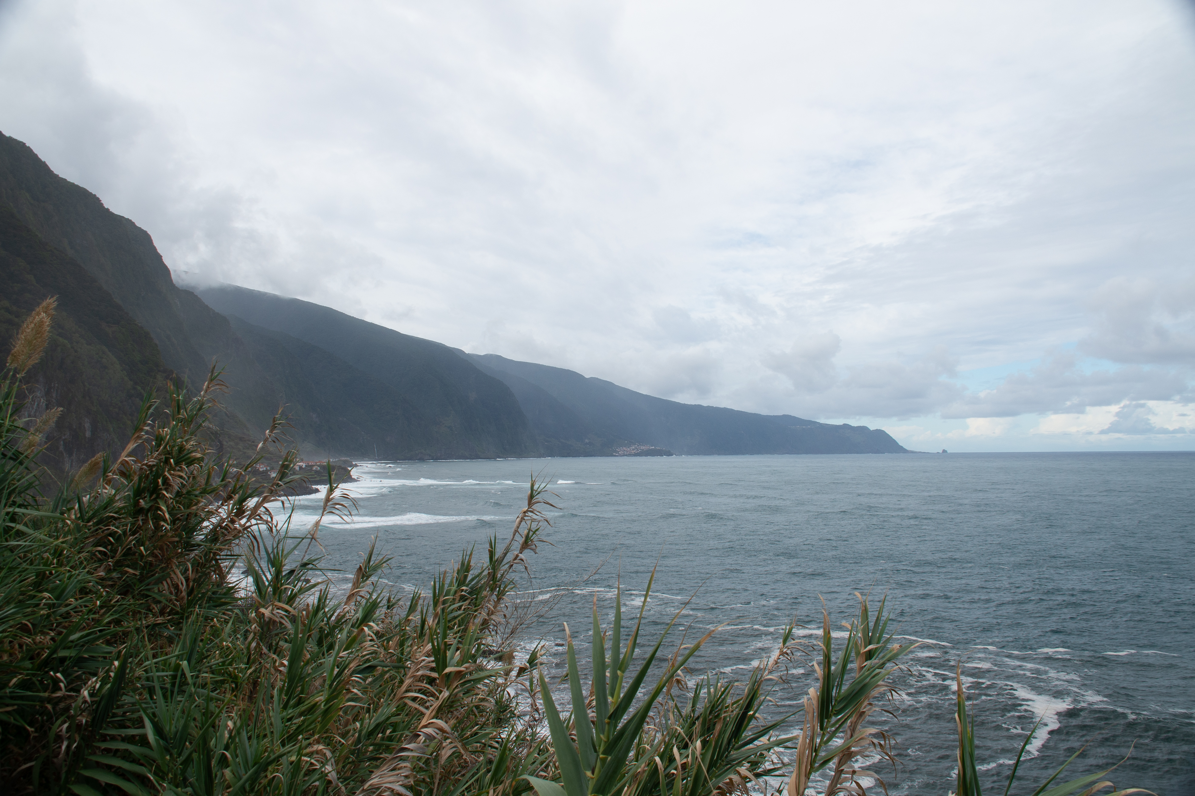 The sky is overcast with clouds, and the waves gently crash against the shore