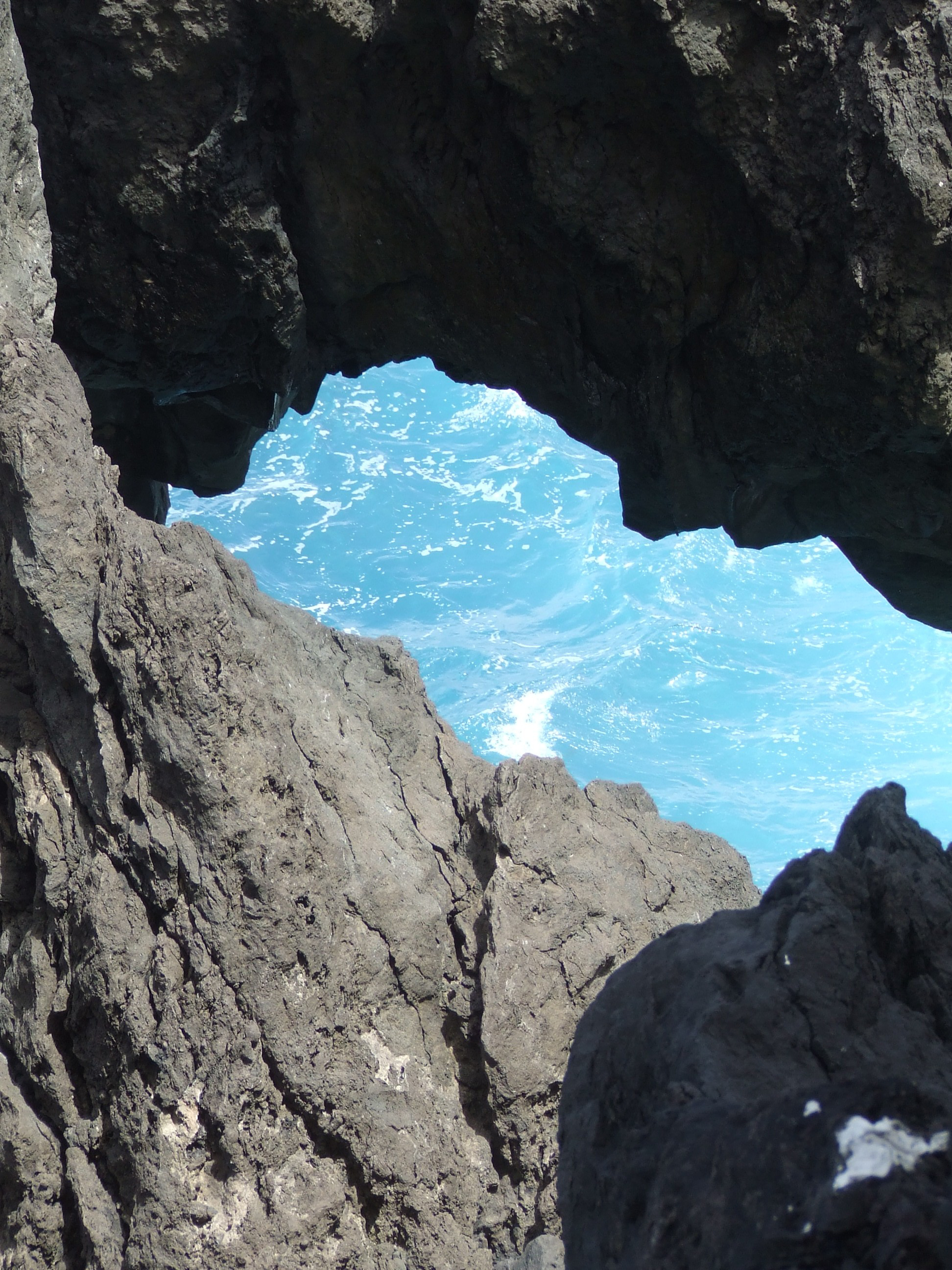 a view from inside a rocky cave looking out towards the ocean