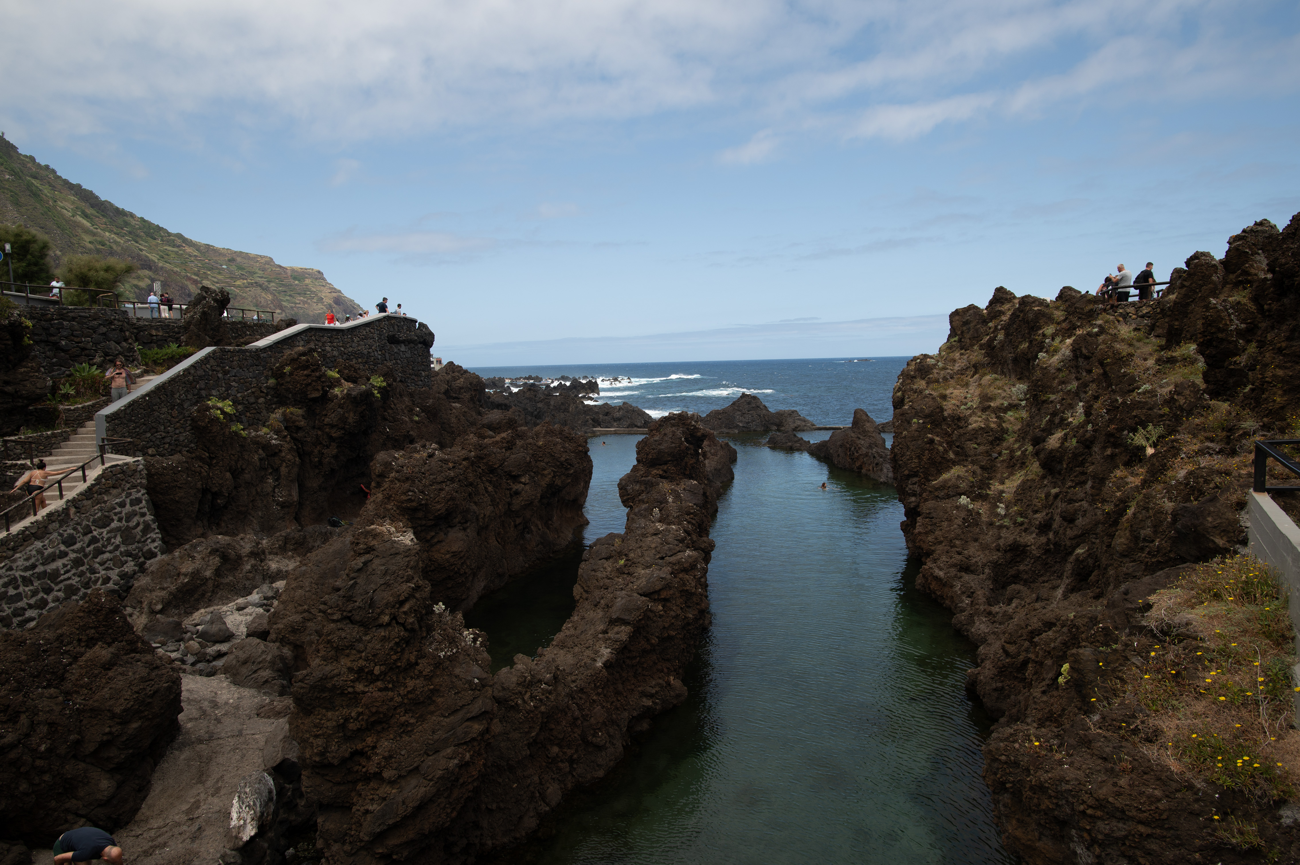 rugged volcanic rock formations and a narrow inlet of water leading to the ocean