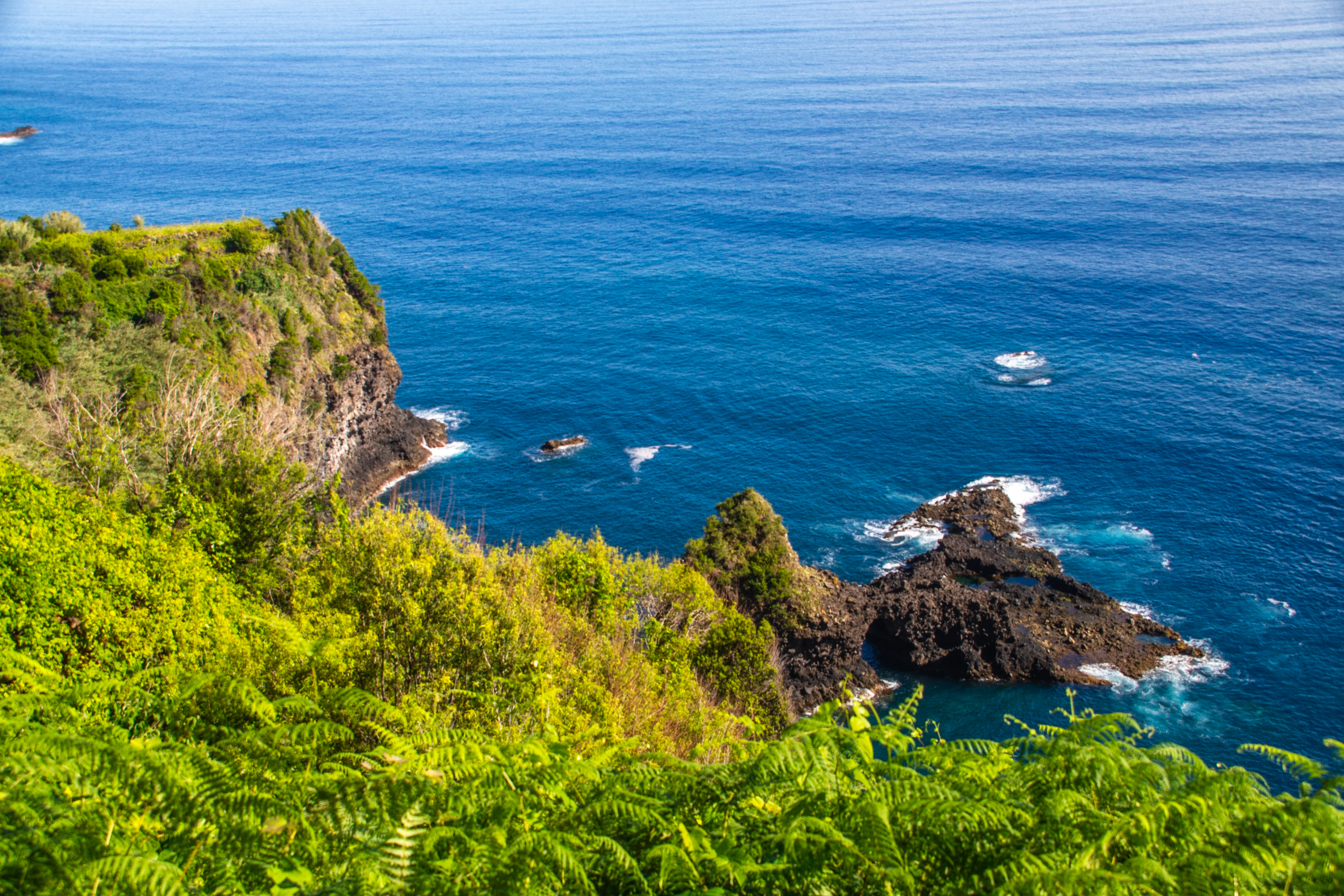 waves crashing against the rocks and a small cave or archway in the cliffs
