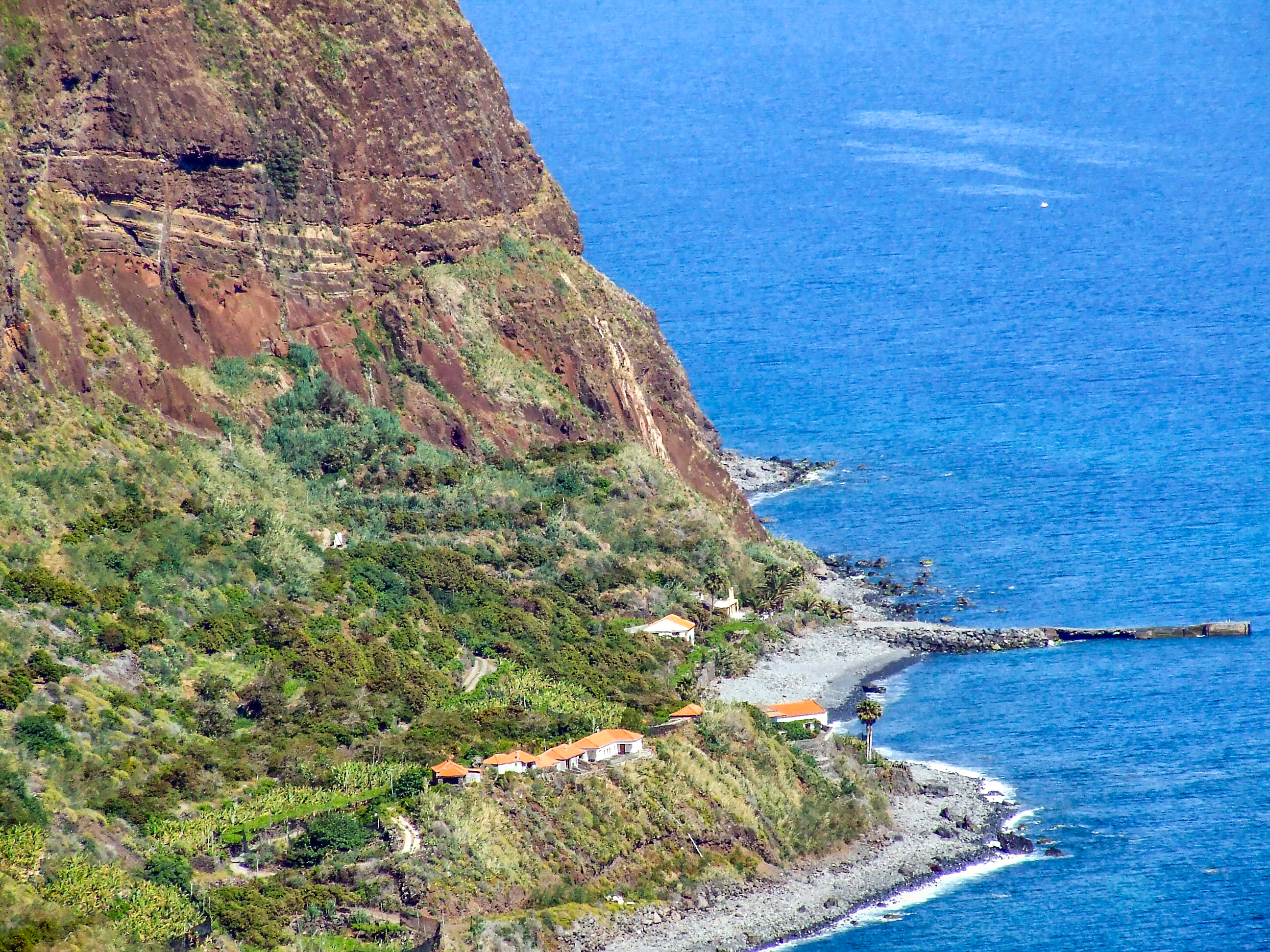At the base of the cliff, there are a few small buildings