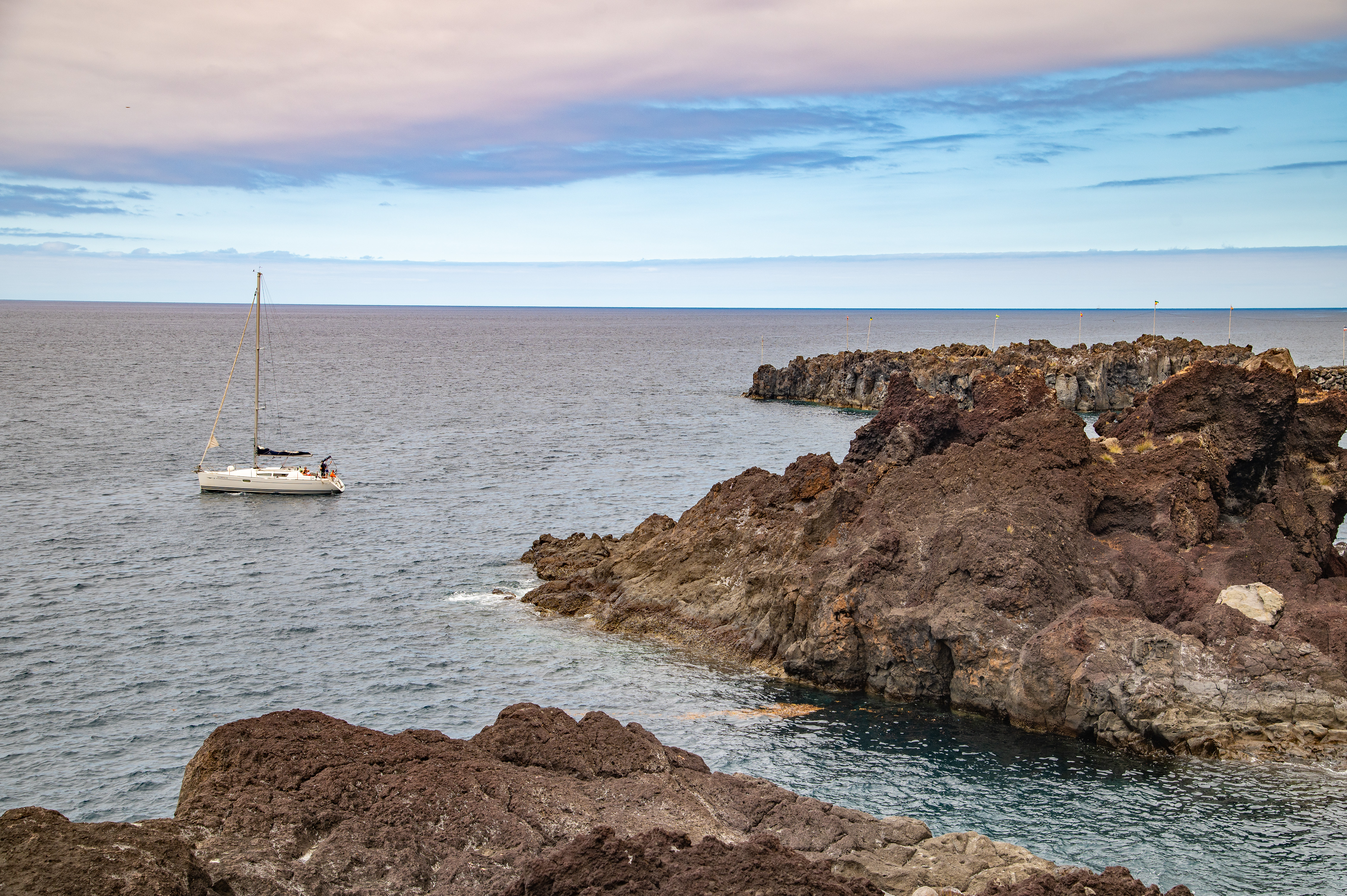 A sailboat is anchored near the rocks