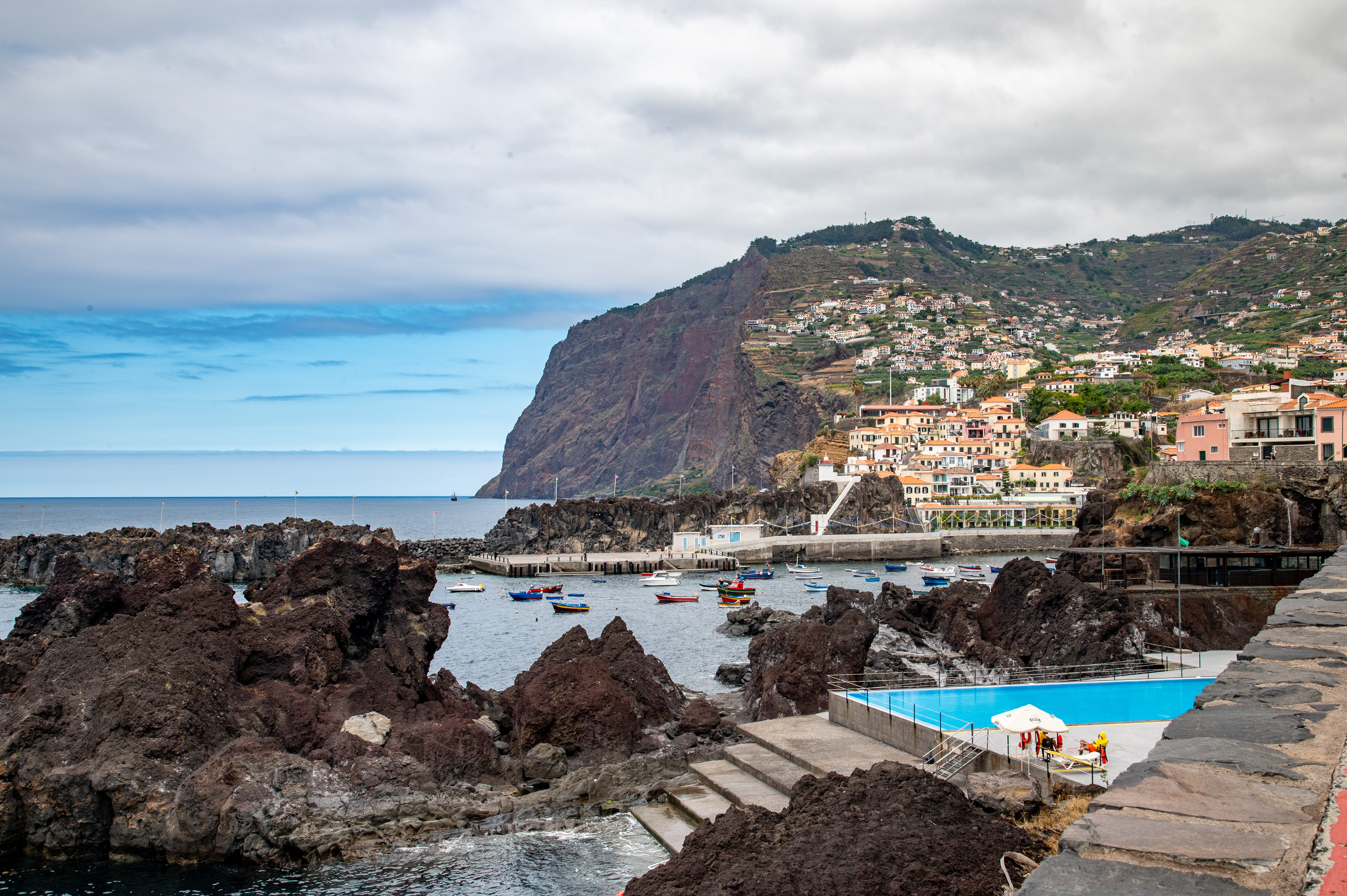 a rocky cliffside with a small harbor filled with boats