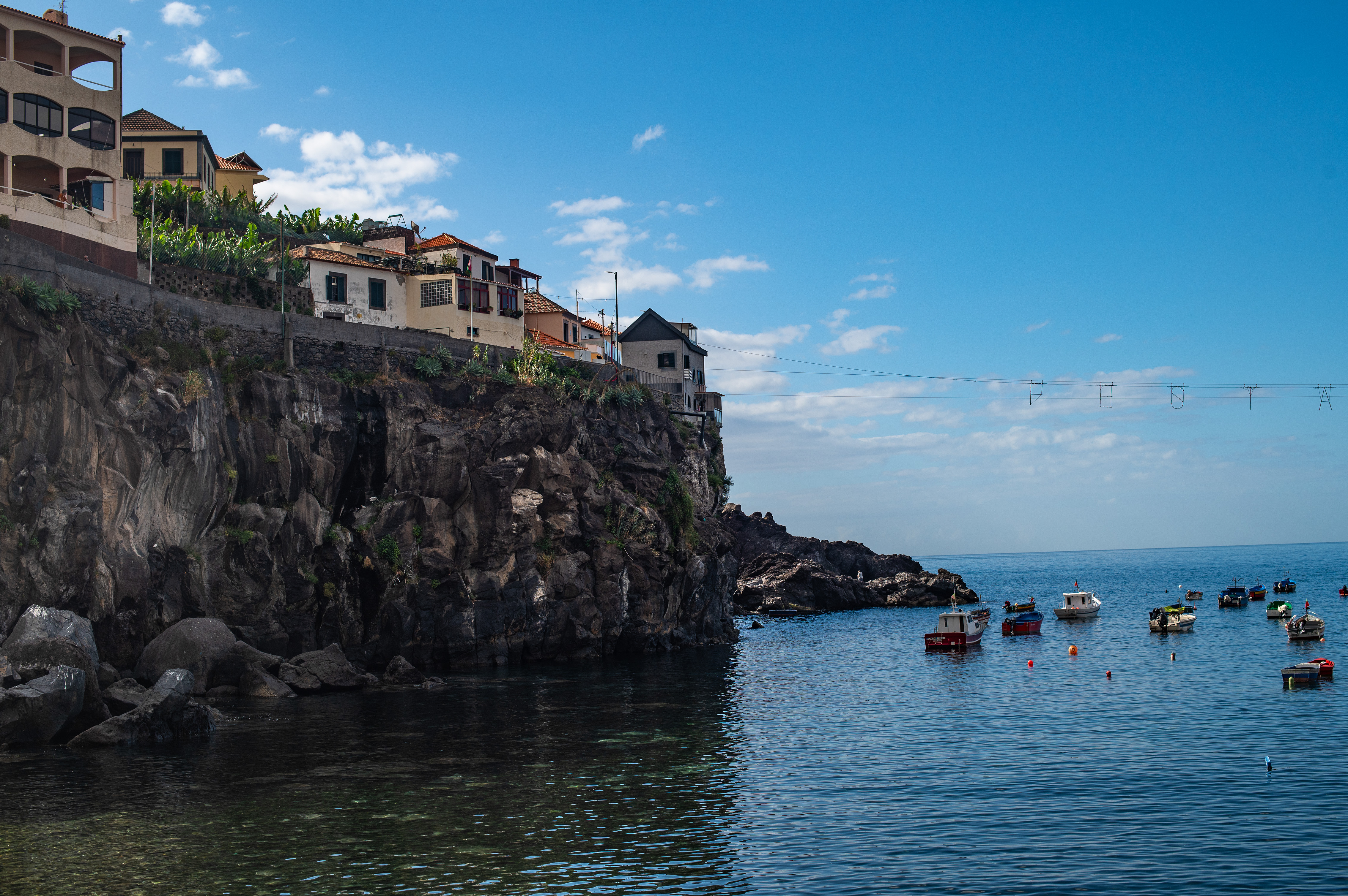 Several small boats are anchored in the clear, calm waters near the shore