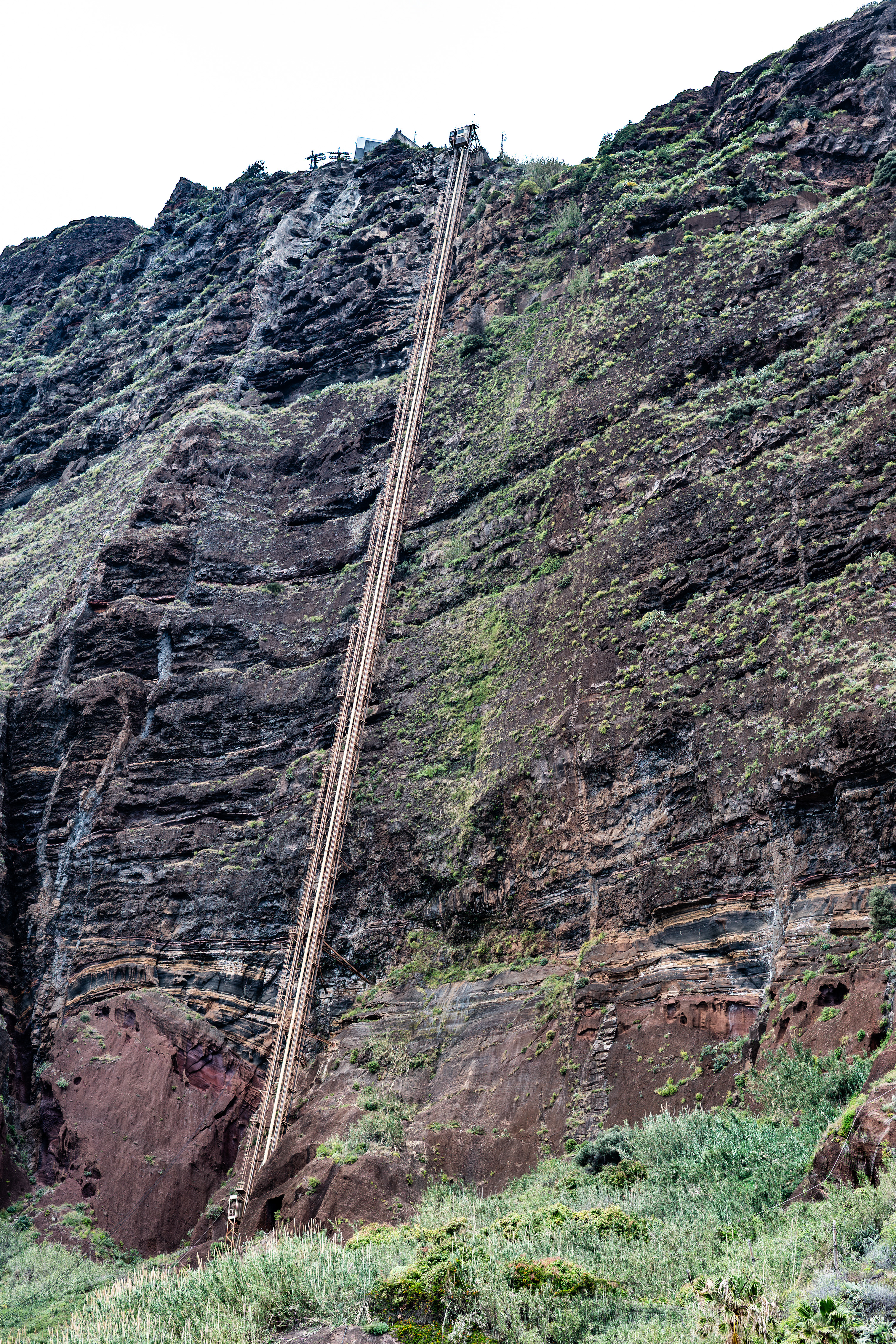 a steep mountain slope with a cable car track running up the side
