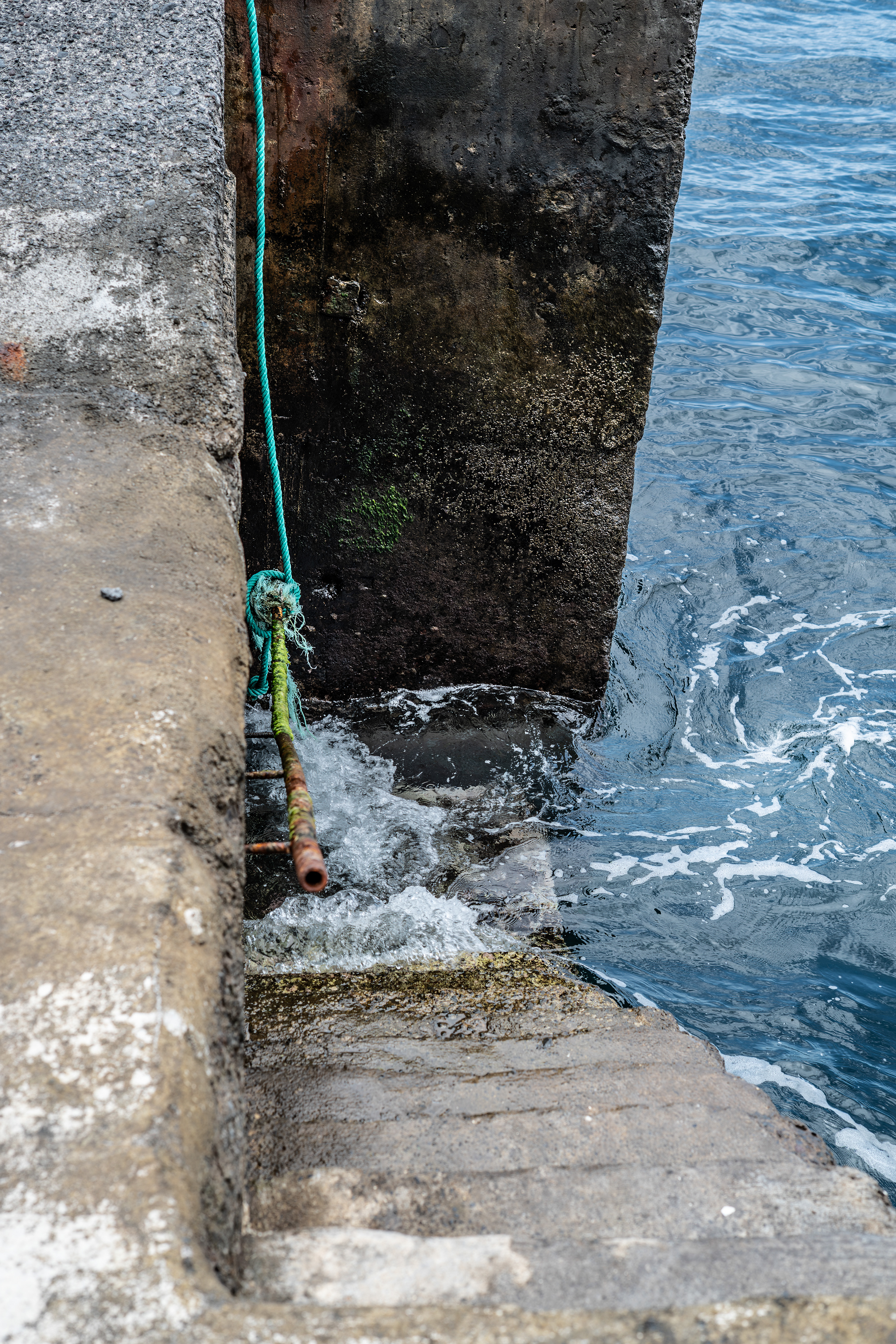 A green rope is tied to a metal pipe