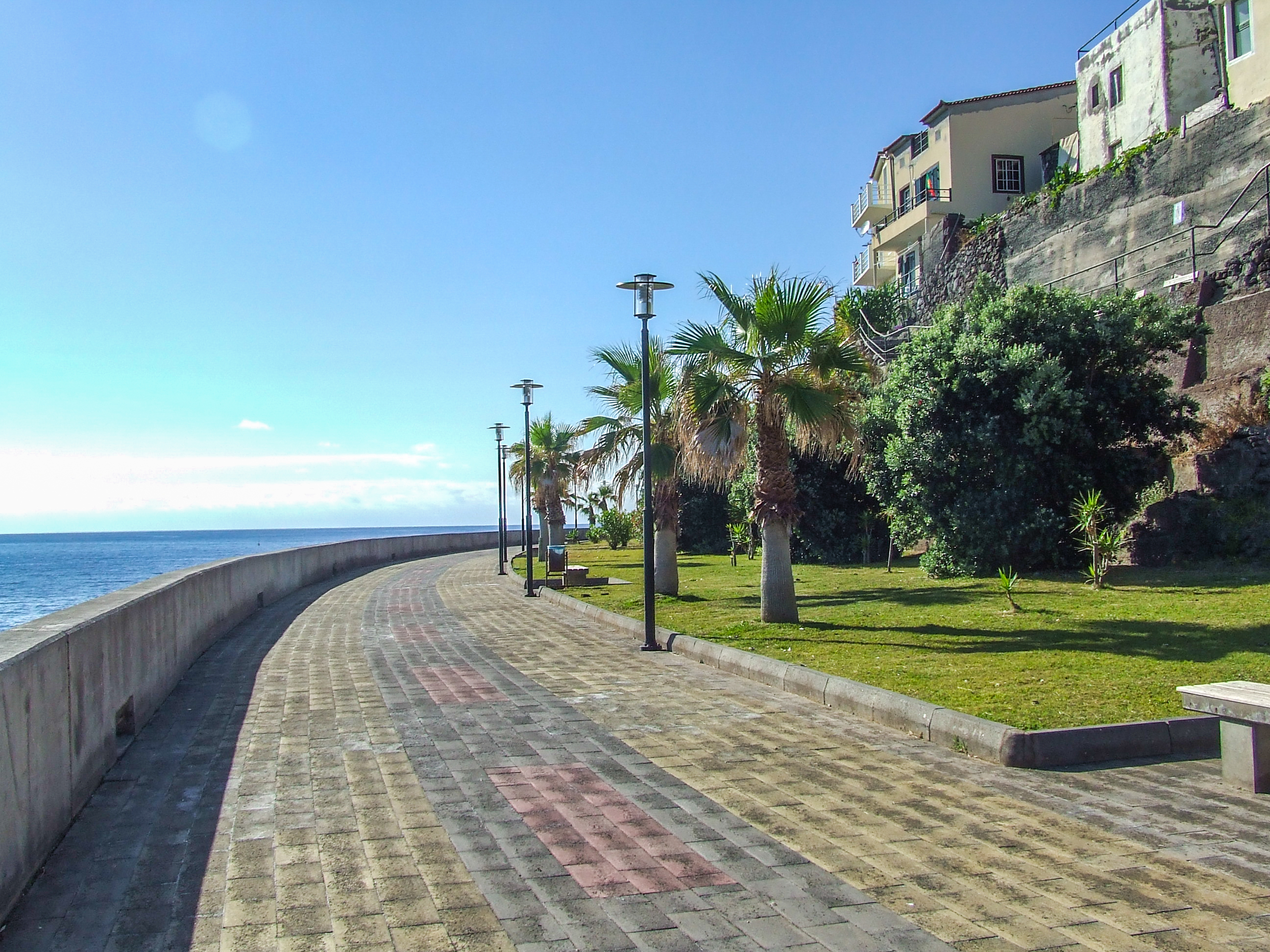 The path curves along the coastline under a clear blue sky