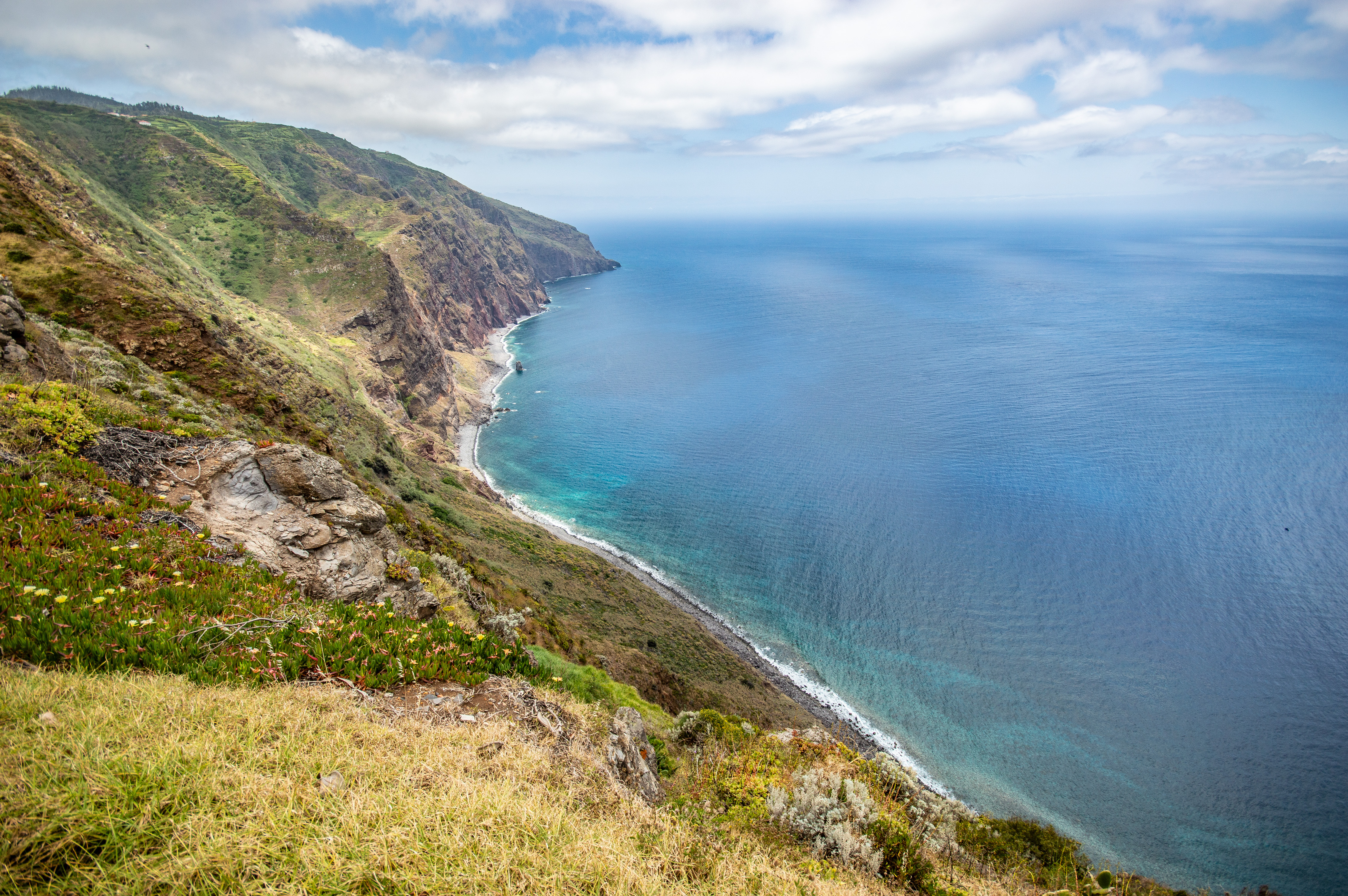 steep, grassy cliffs and a winding path leading down to a secluded beach