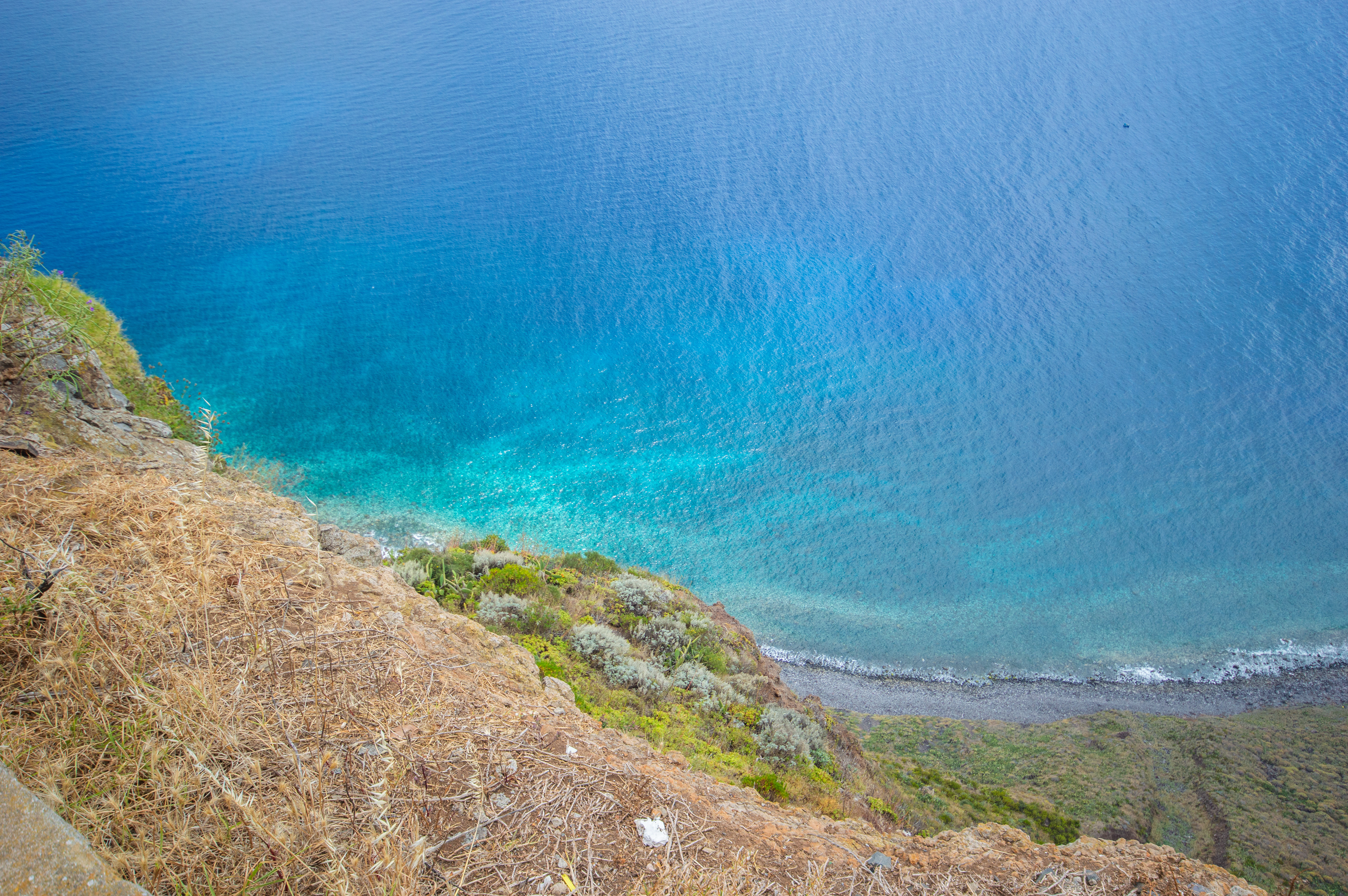 blue waters gently lapping against a rocky and grassy shoreline