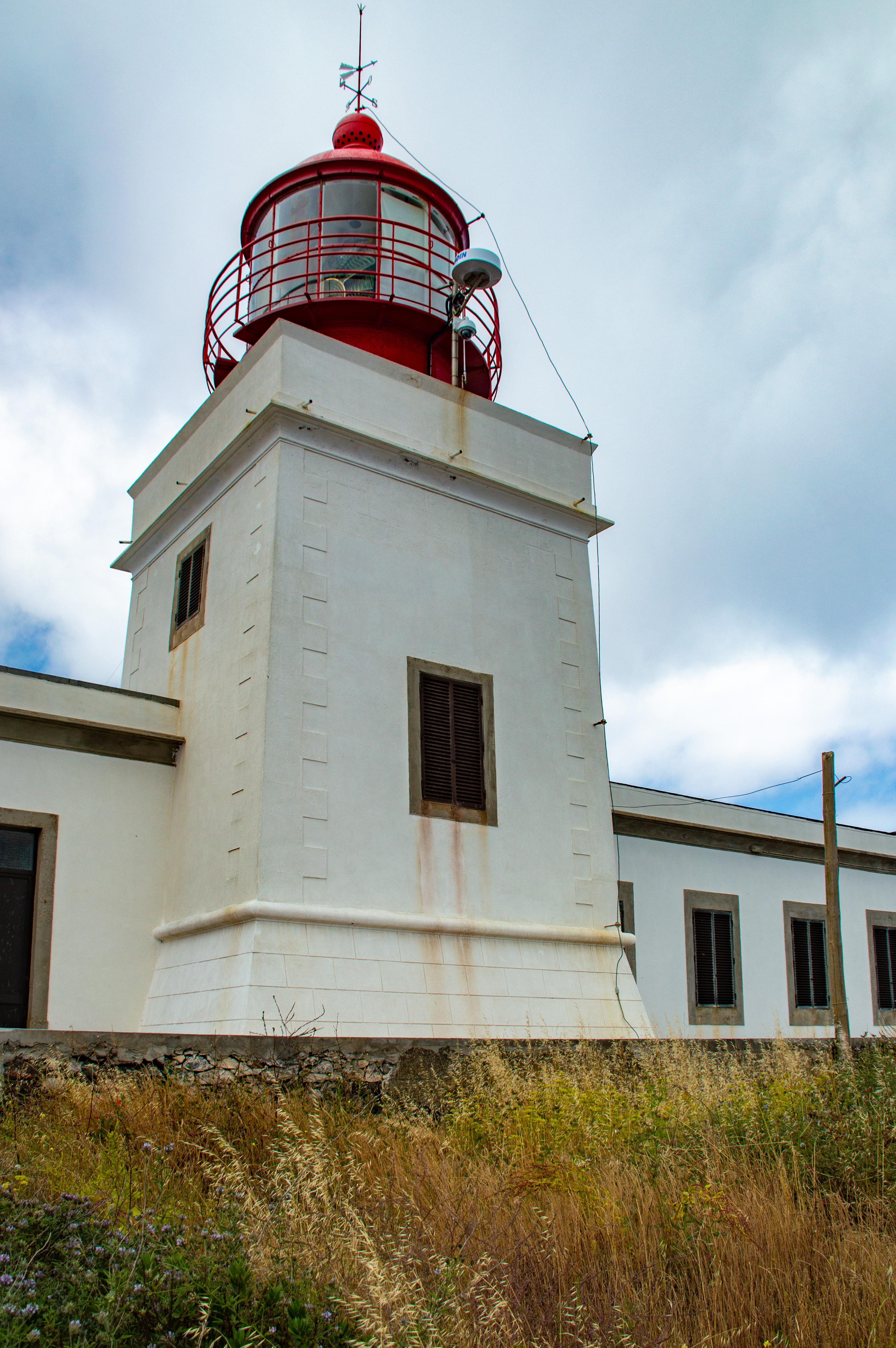 a lighthouse with a white structure and a red lantern room at the top