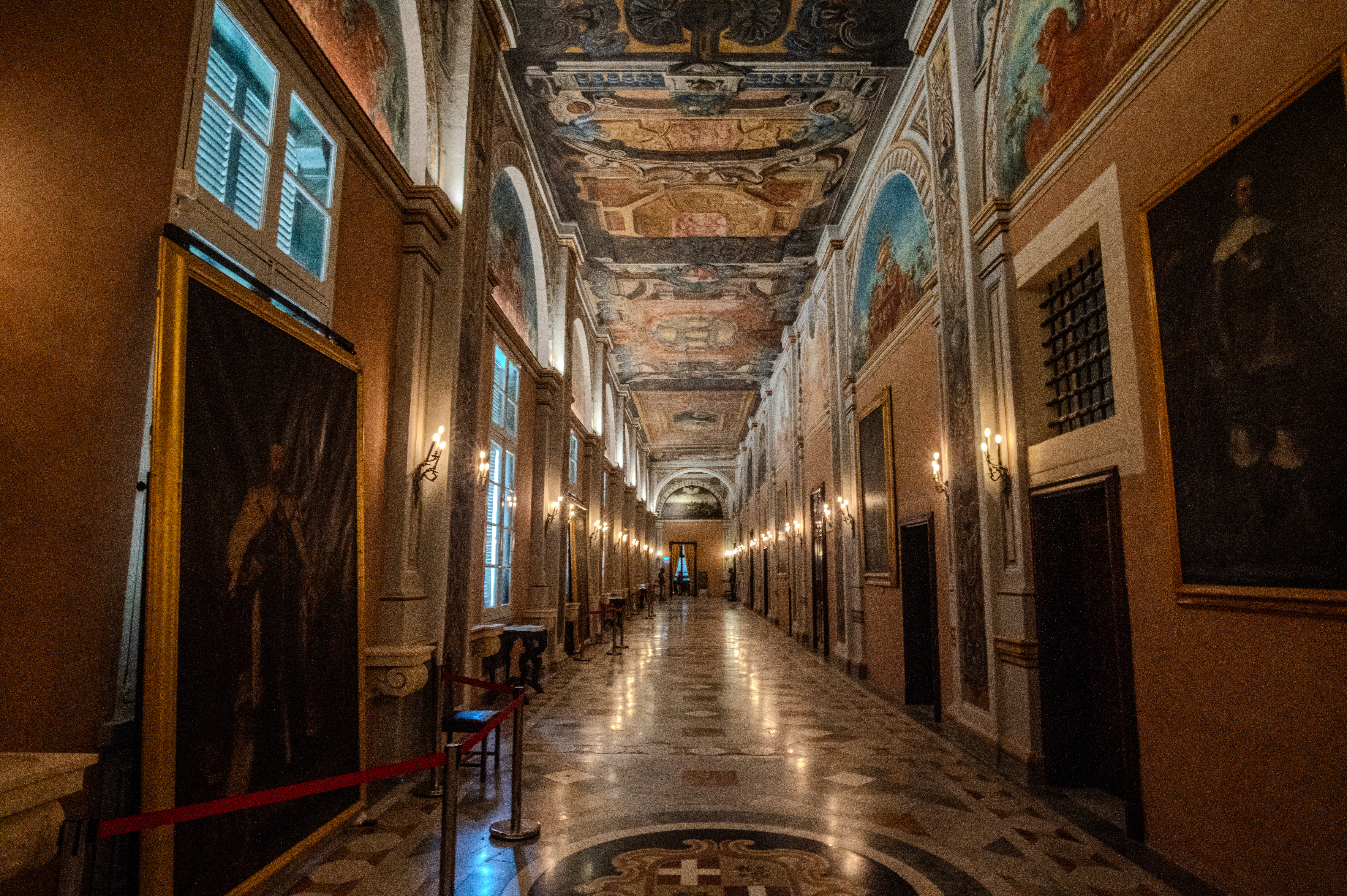 a long, ornately decorated hallway with a high, intricately painted ceiling