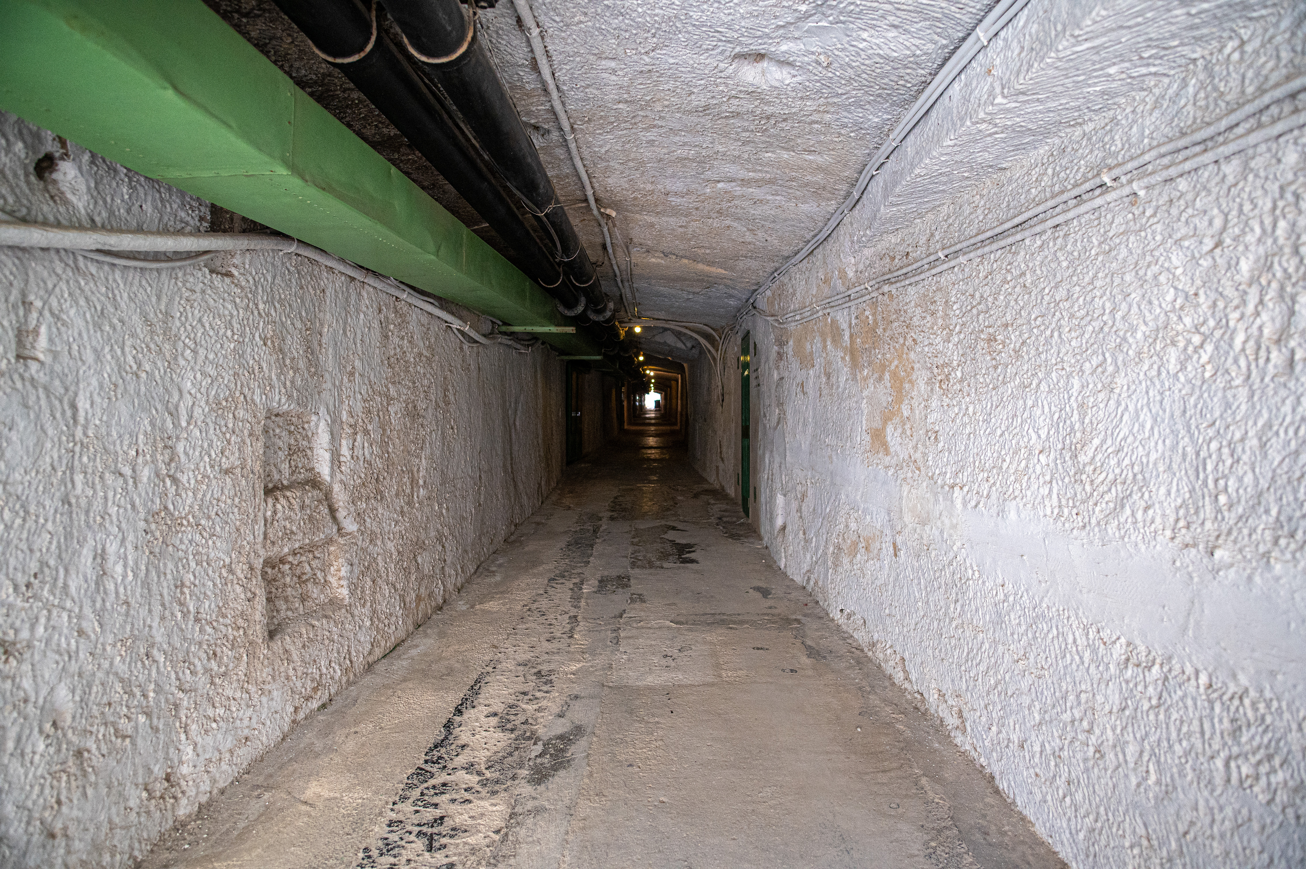 an underground tunnel with rough, textured walls and a concrete floor