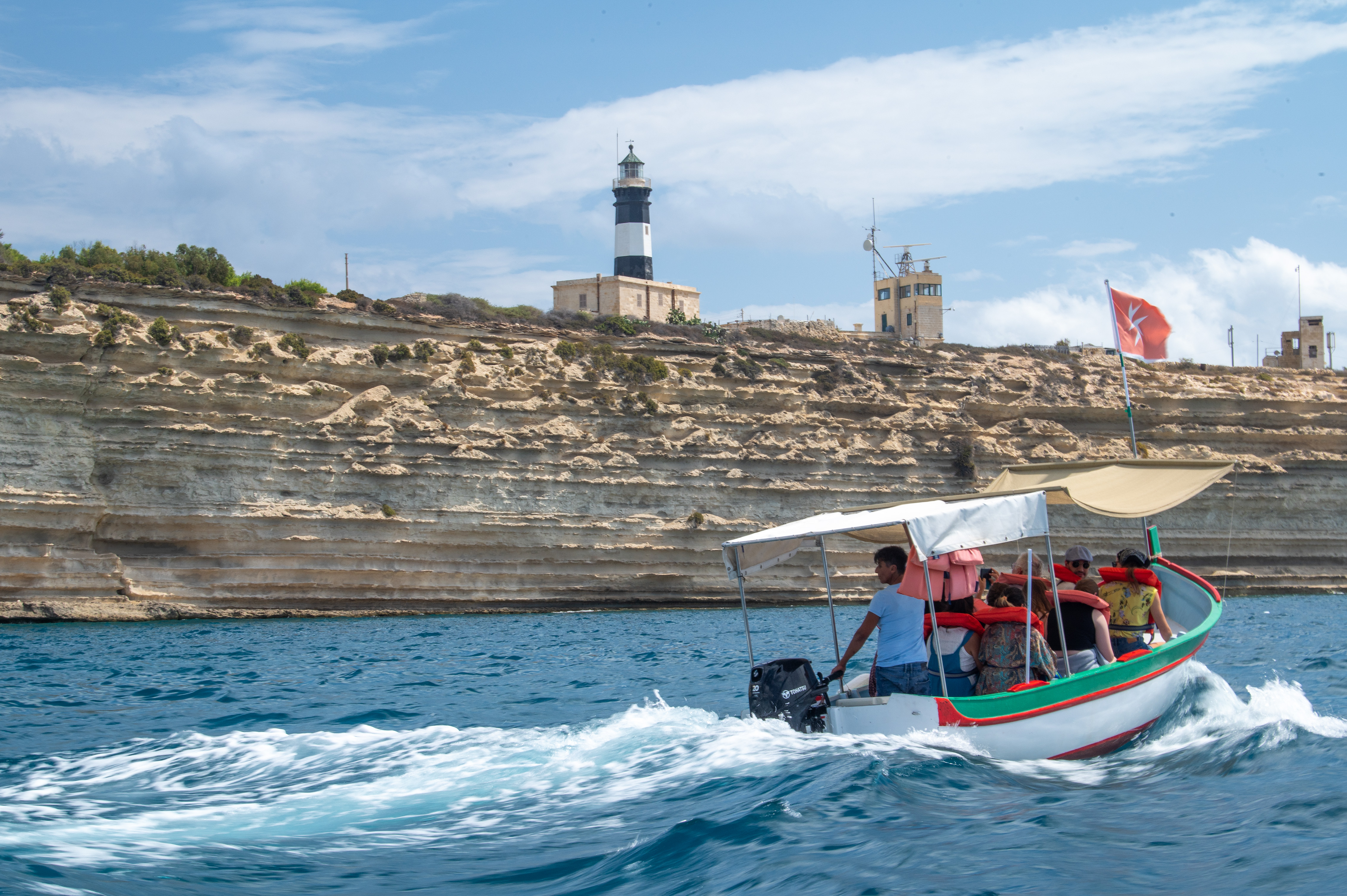 A small boat with several passengers is seen navigating through the water