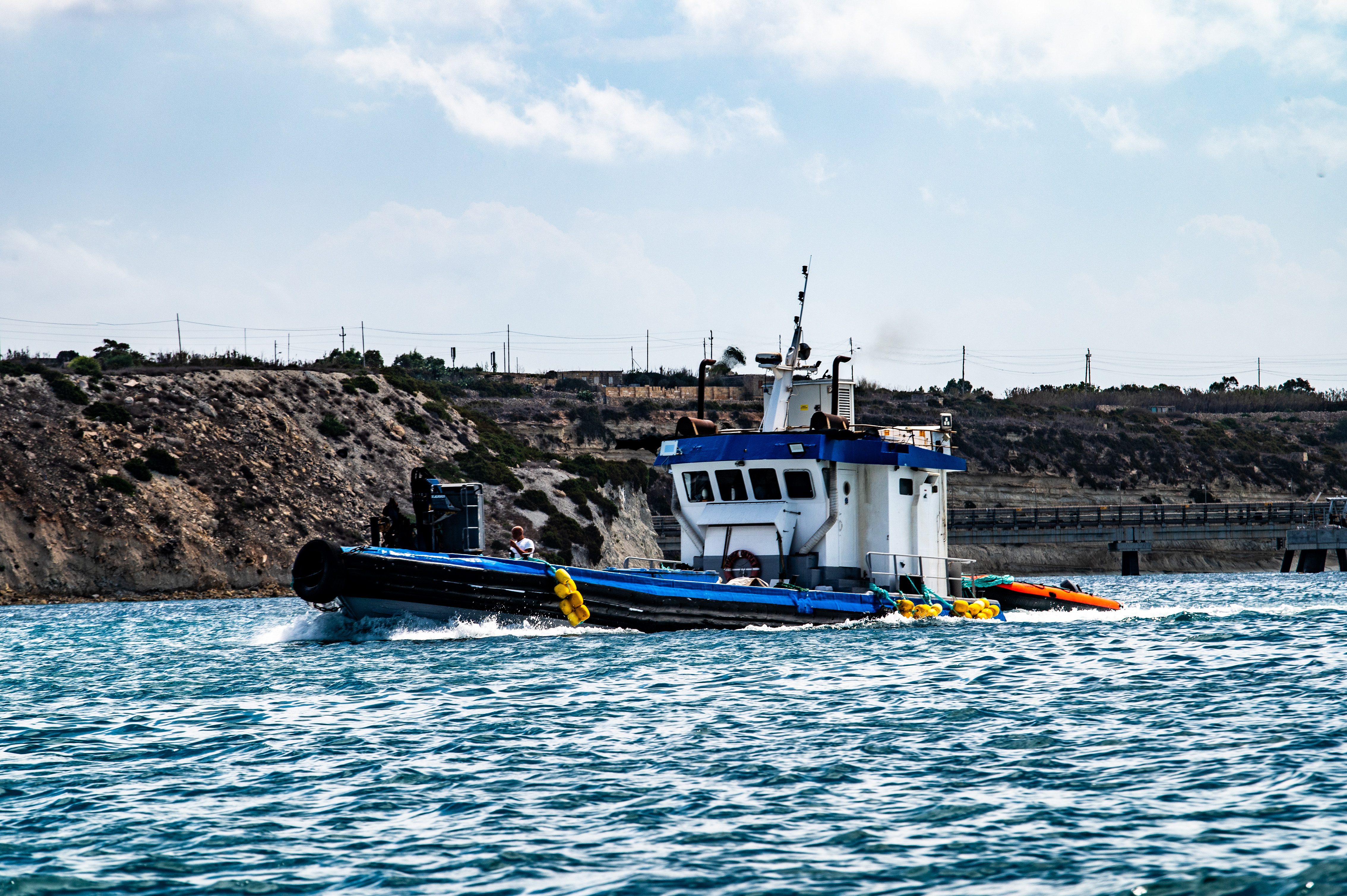a small boat with a blue and white color scheme navigating through a body of water