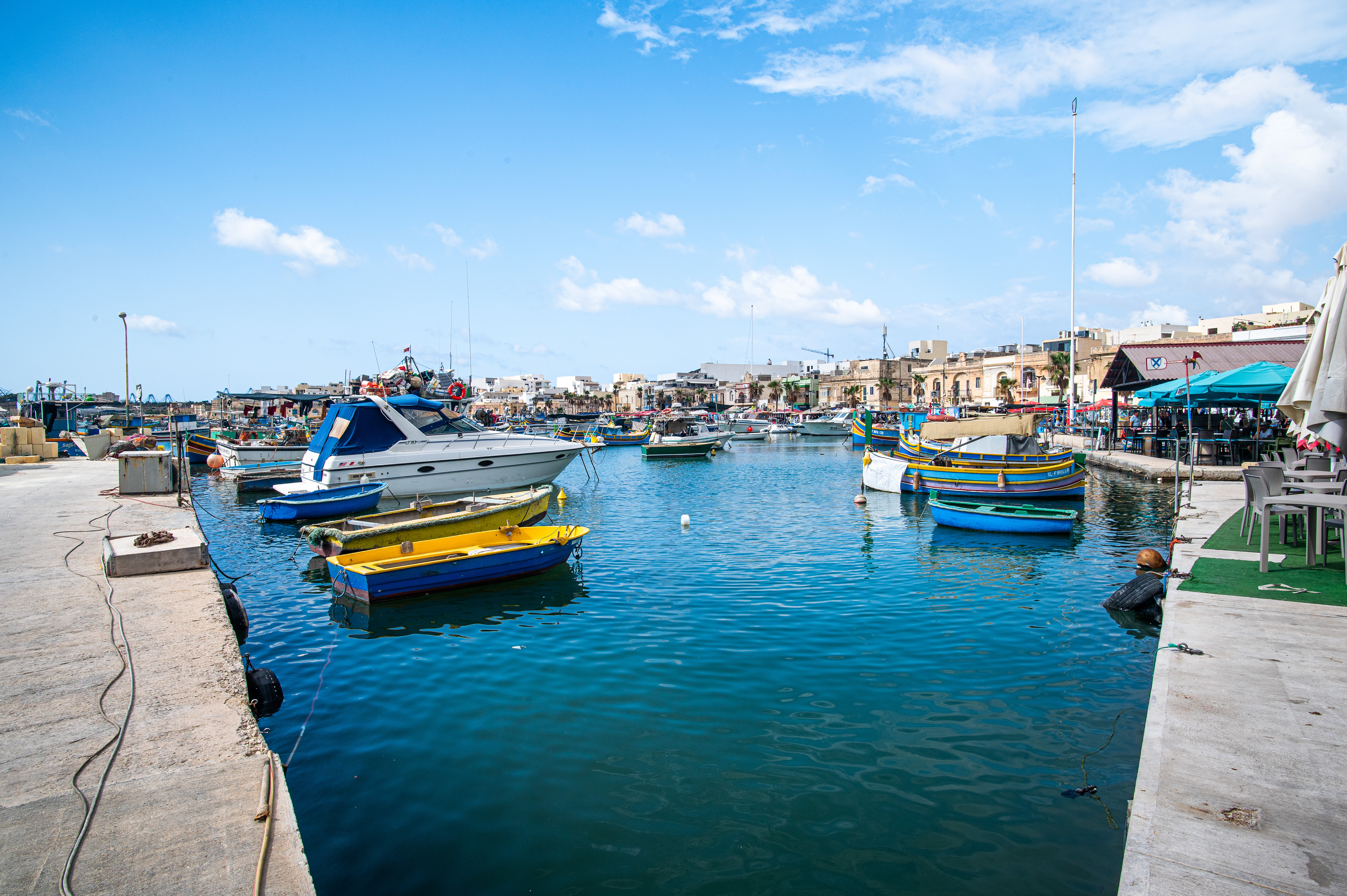 The water is calm and clear, reflecting the boats and the surrounding environment