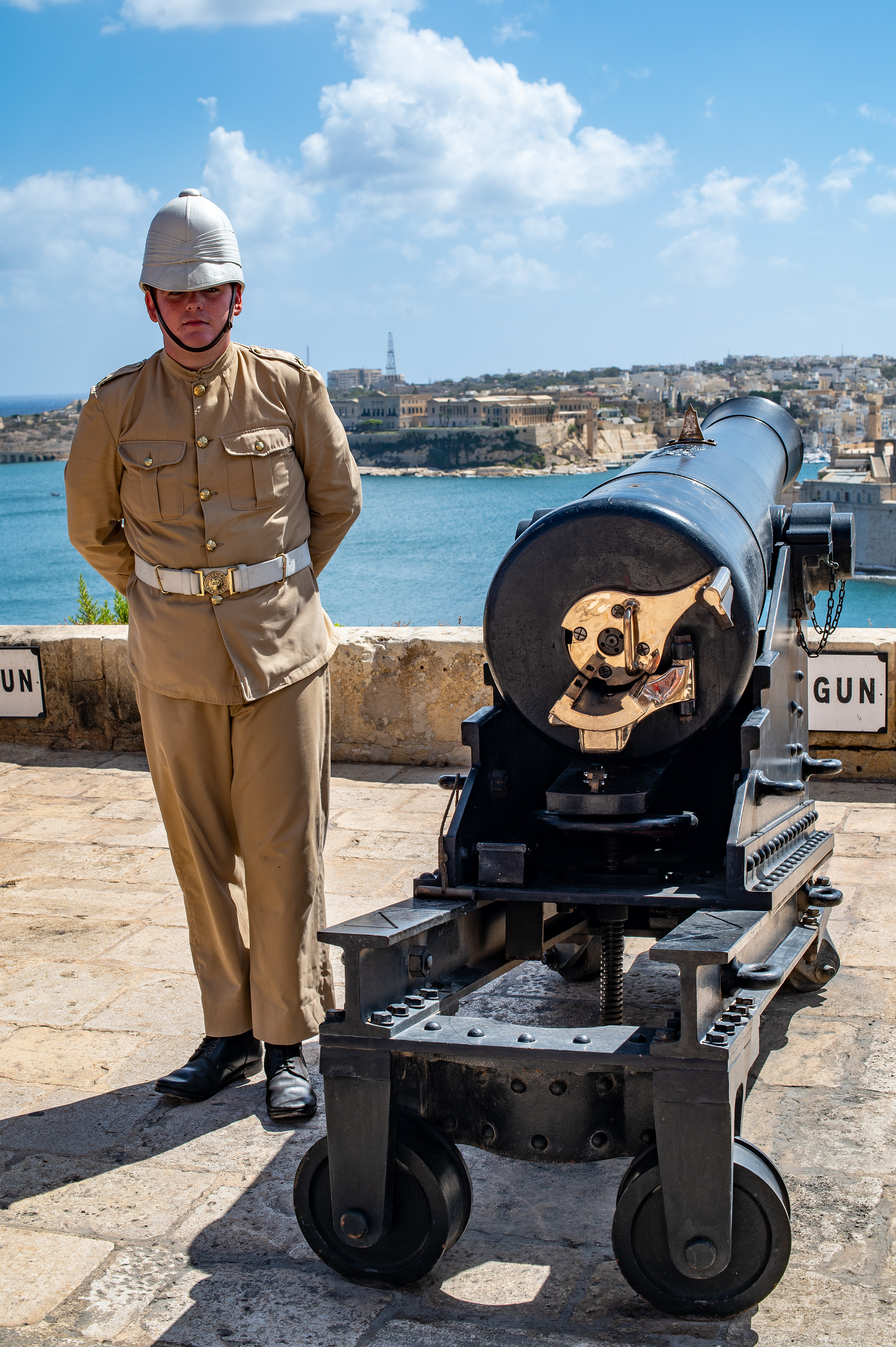 a person in a historical military uniform standing next to an old cannon
