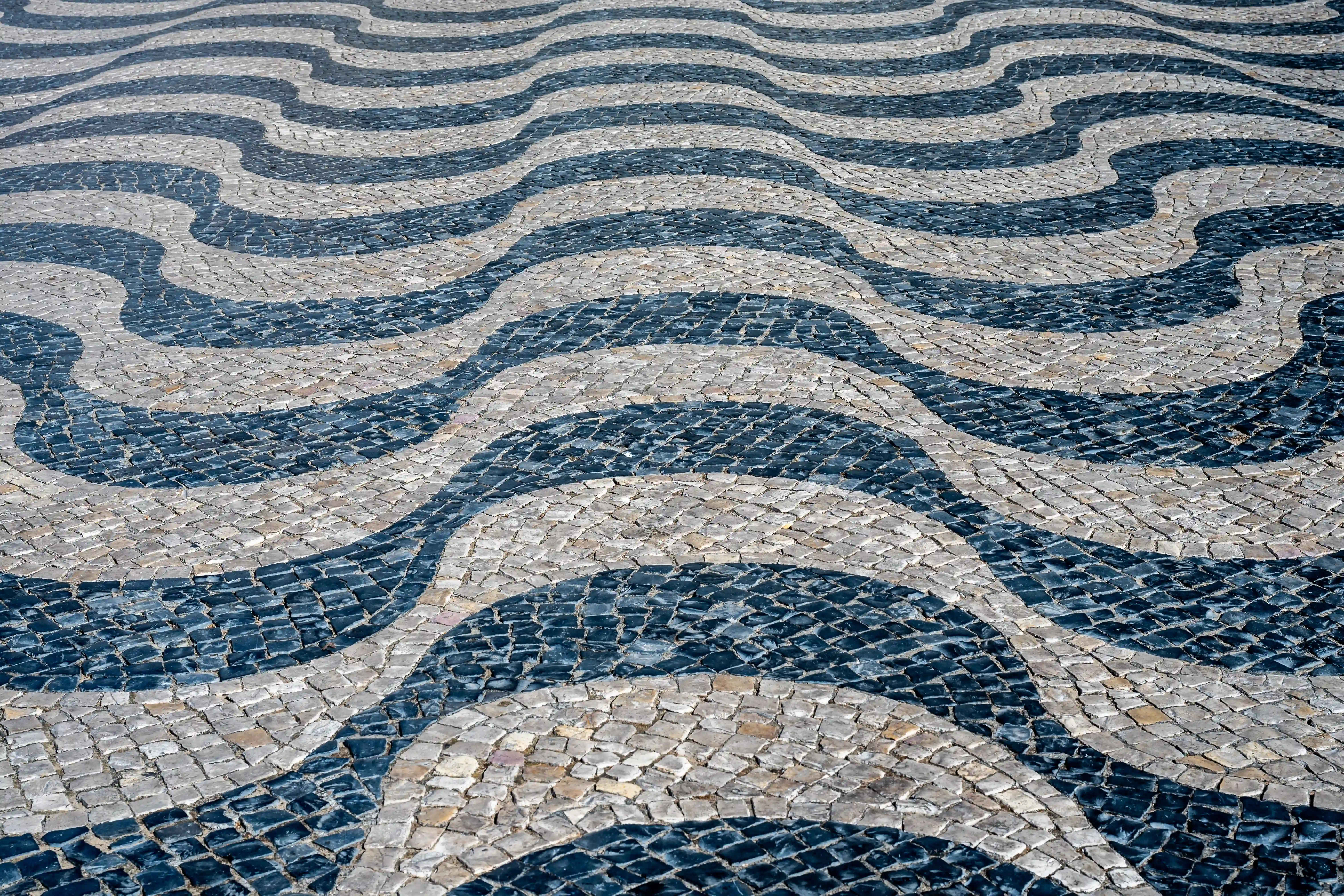 A textured, close-up view of a cobbled pavement with a distinctive black and white wavy, moiré-like pattern.