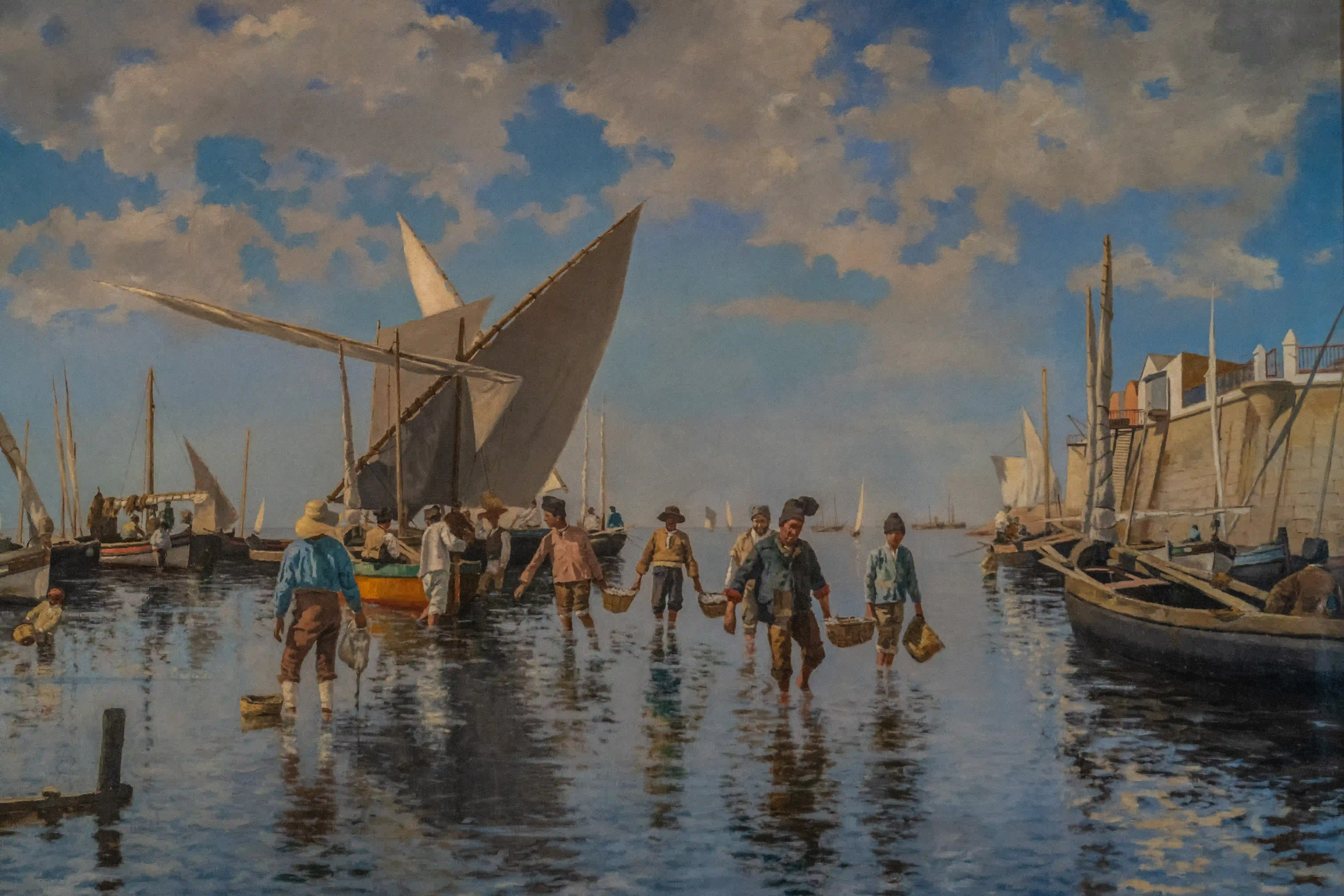 A painting of several men and boys wading through shallow water in a harbour, carrying baskets of fish. Sailboats and a stone building are in the background.