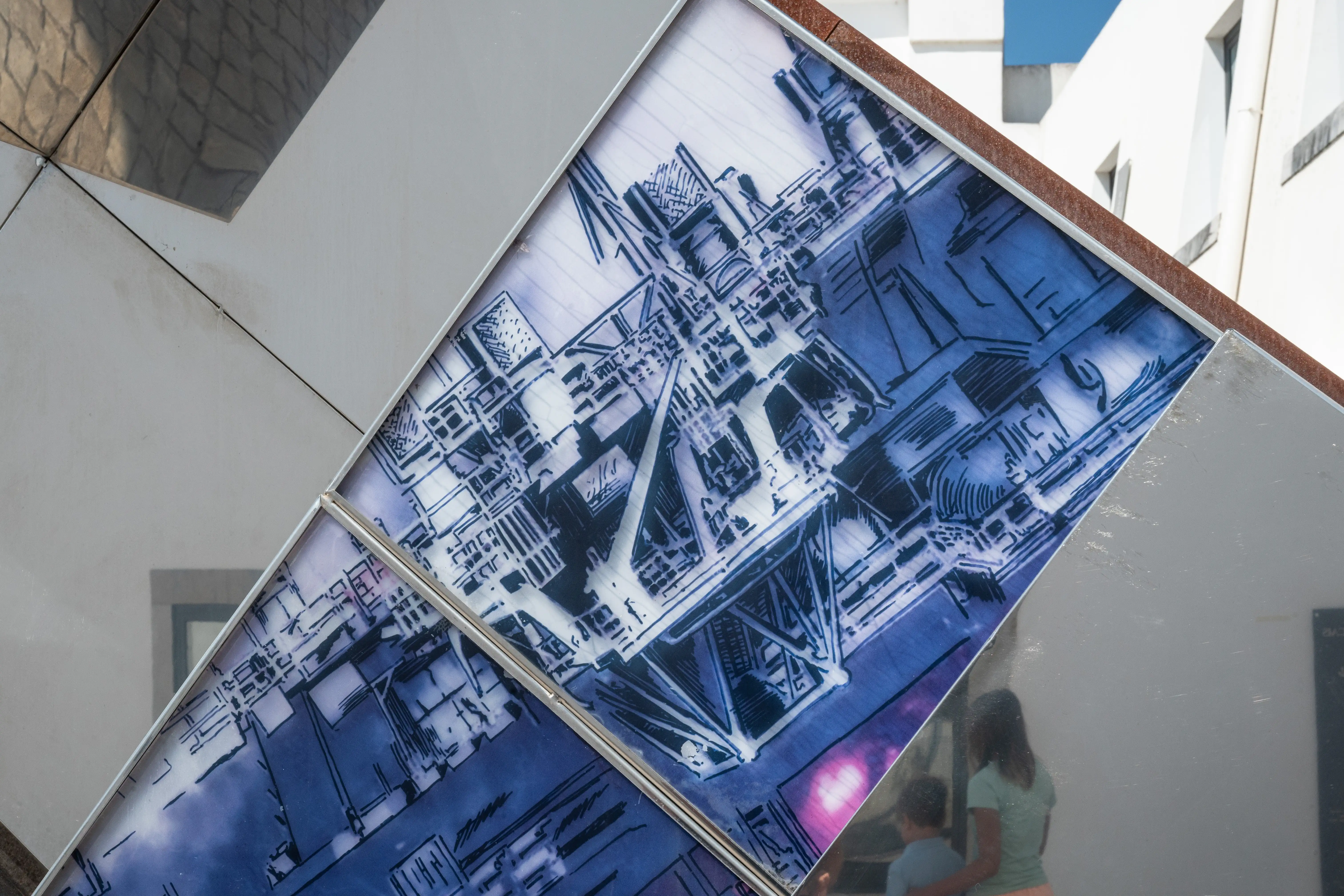 Reflective diamond-pattern metal panels showing a blue technical illustration and the reflection of two people.
