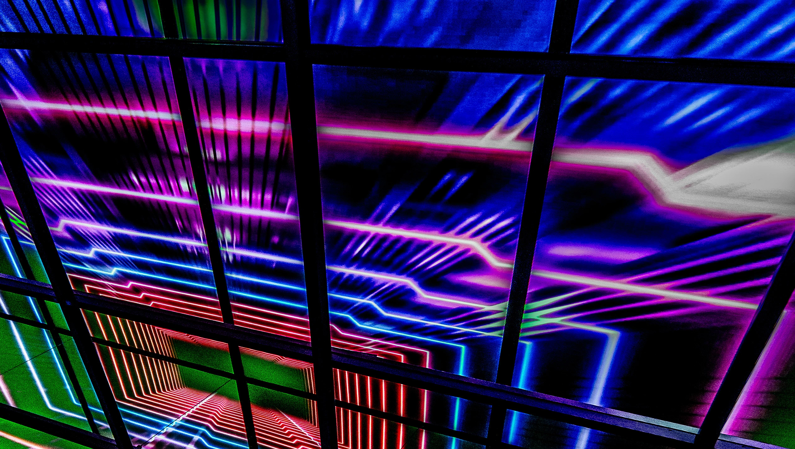 Abstract image of a perspective tunnel made of glowing pink and blue neon squares, framed by a dark metal grid.