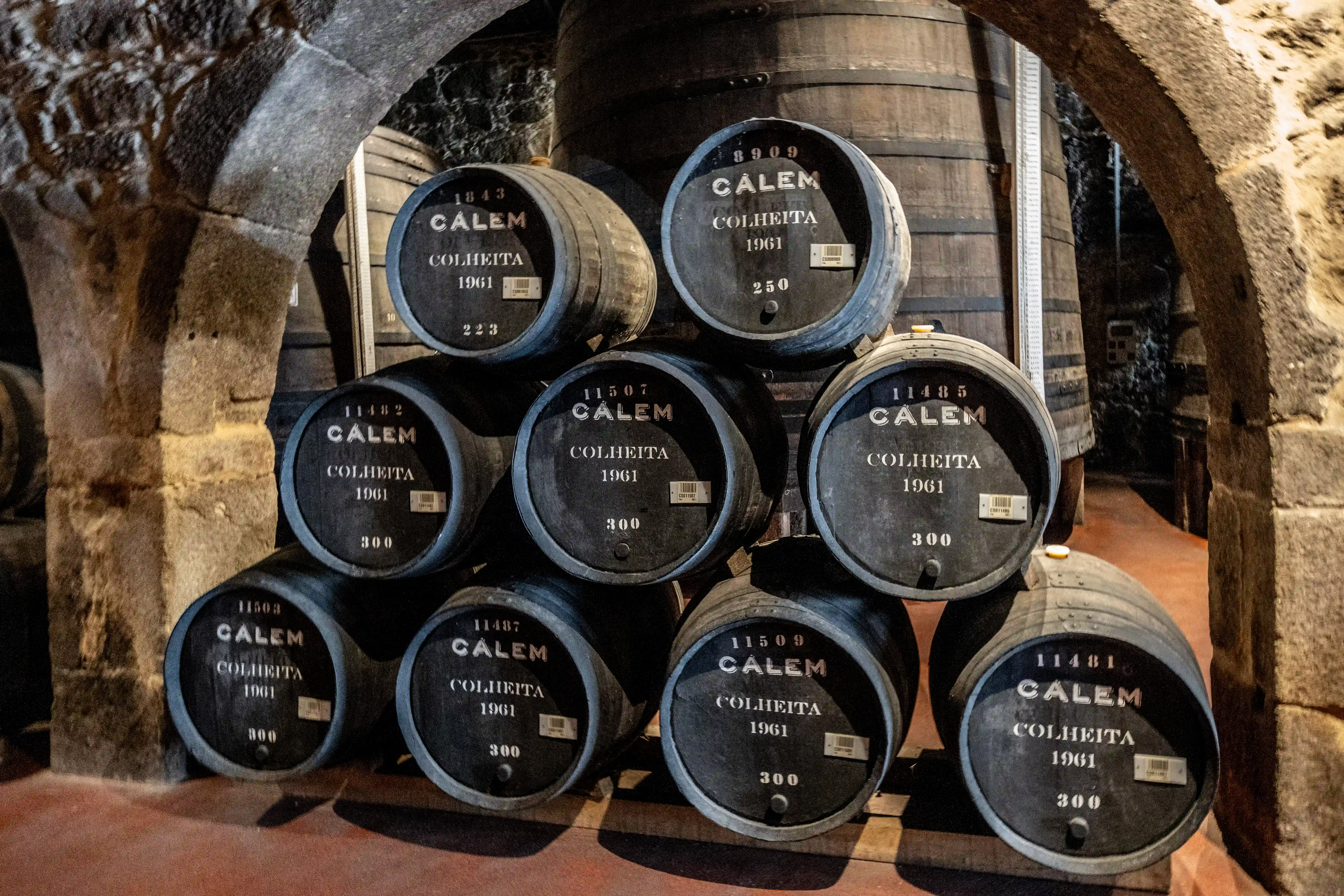 The image shows a wooden rack containing multiple barrels, each labeled 