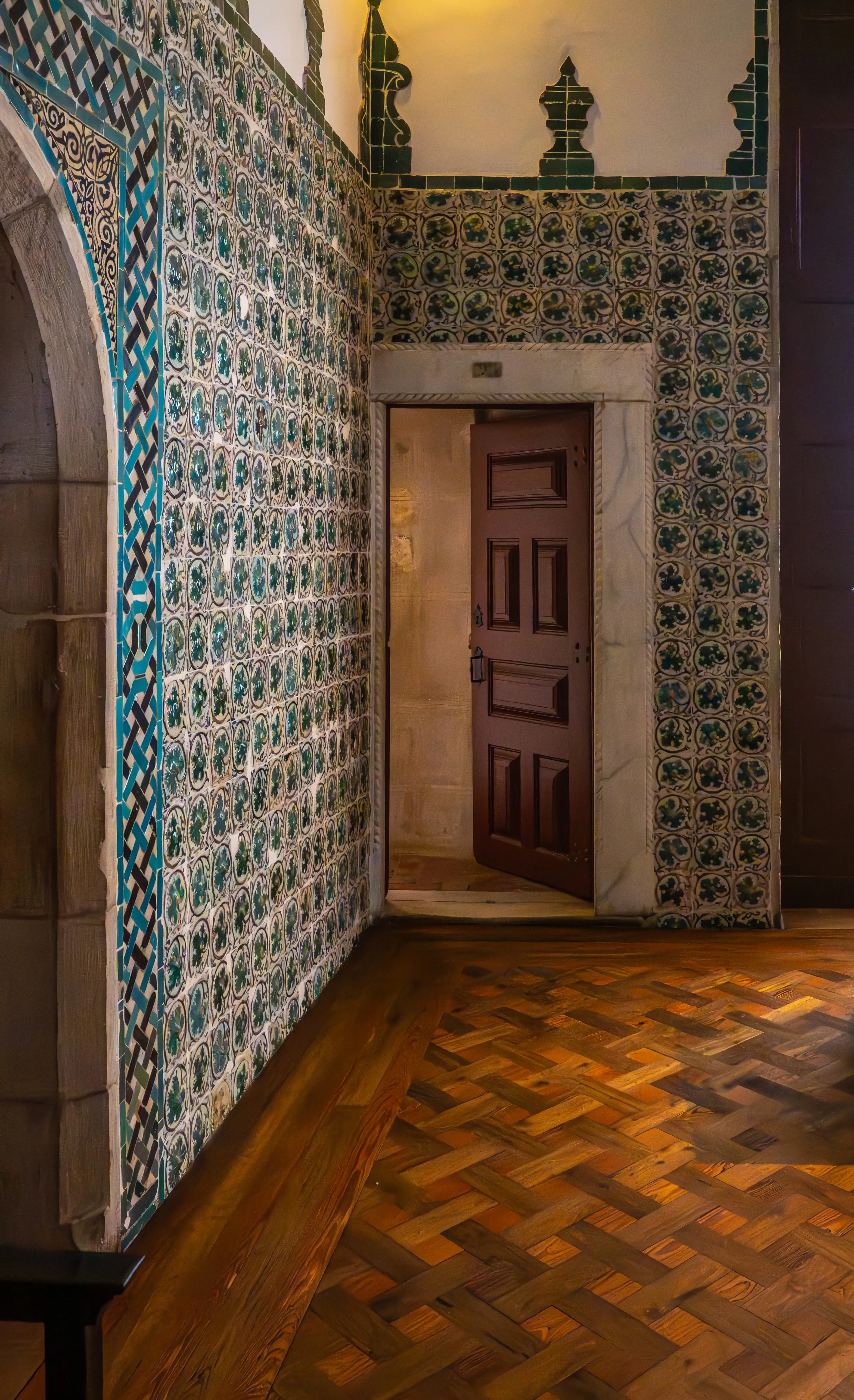A dark, moody interior of a room featuring a tall, bright, cross-paned window with a decorative table in front of it. Ornate tiled walls and a framed painting are visible, along with a wooden floor and ceiling details.