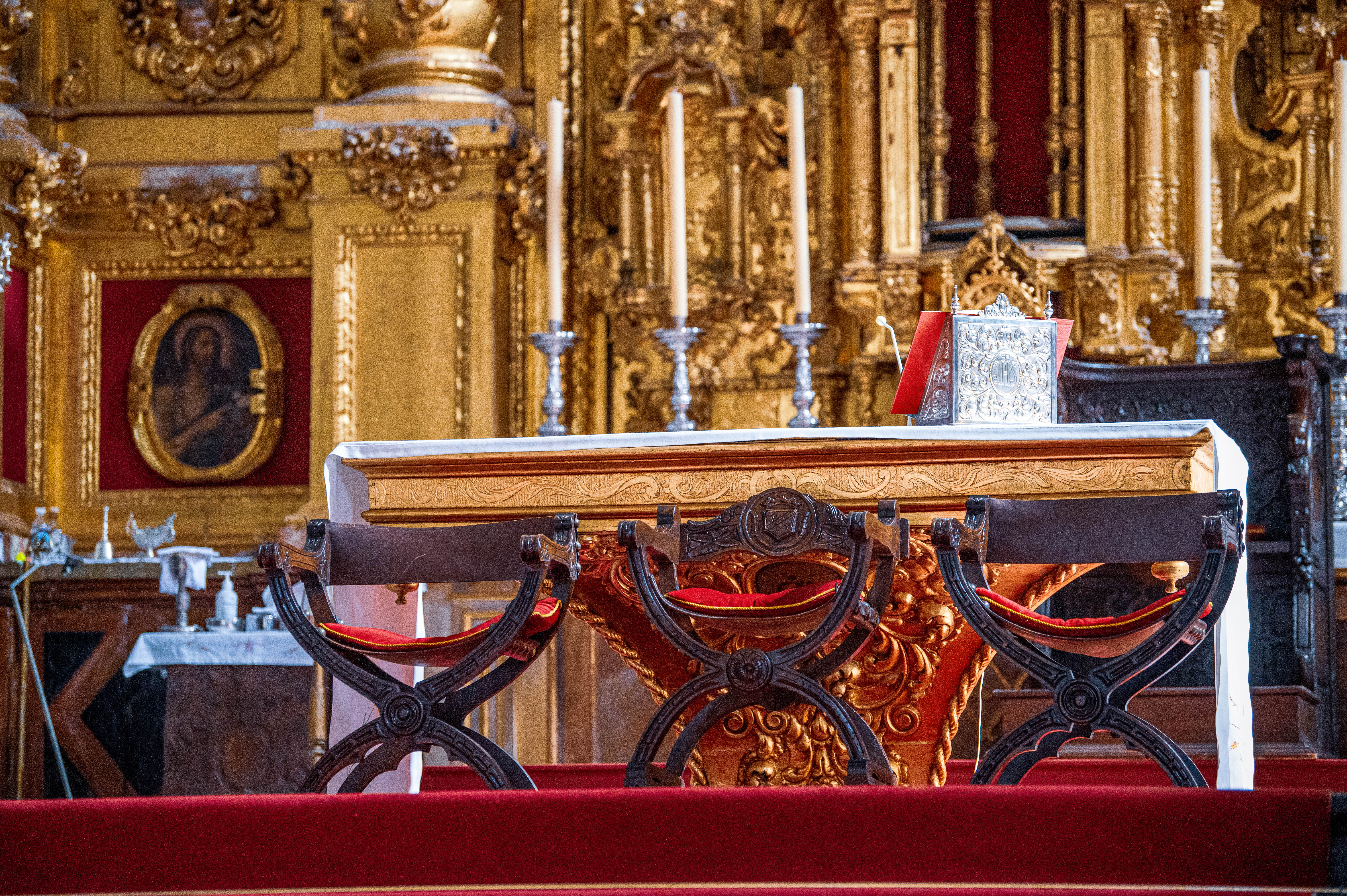 The altar is adorned with several candles, a silver book, and a red bookmark