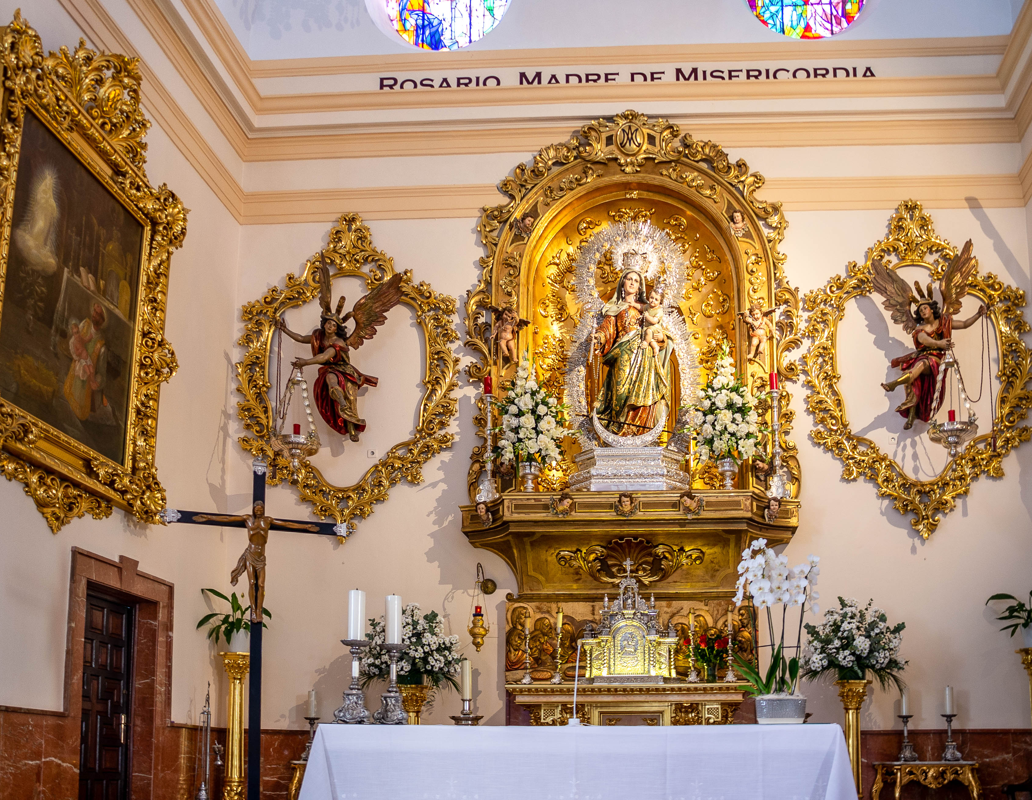a central statue of a religious figure adorned with flowers and surrounded by golden decorations