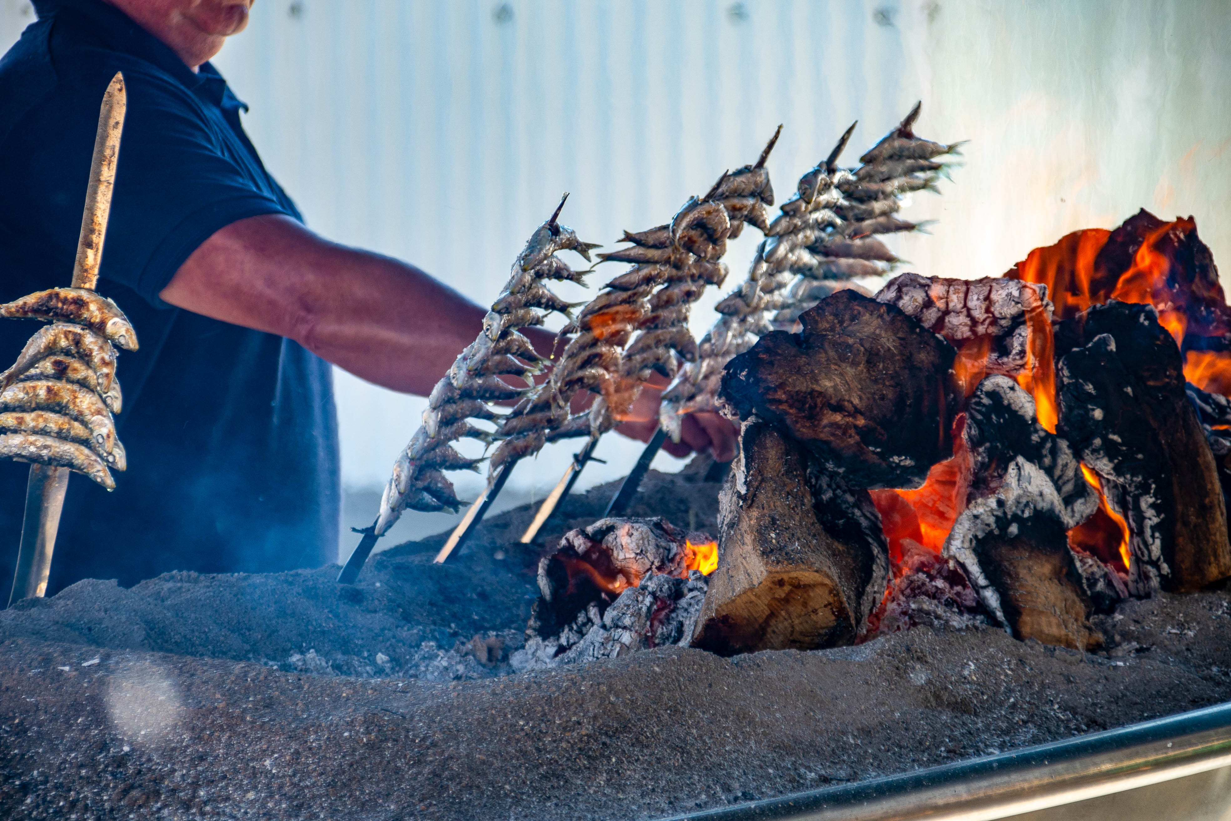 grilling fish on skewers over a wood fire
