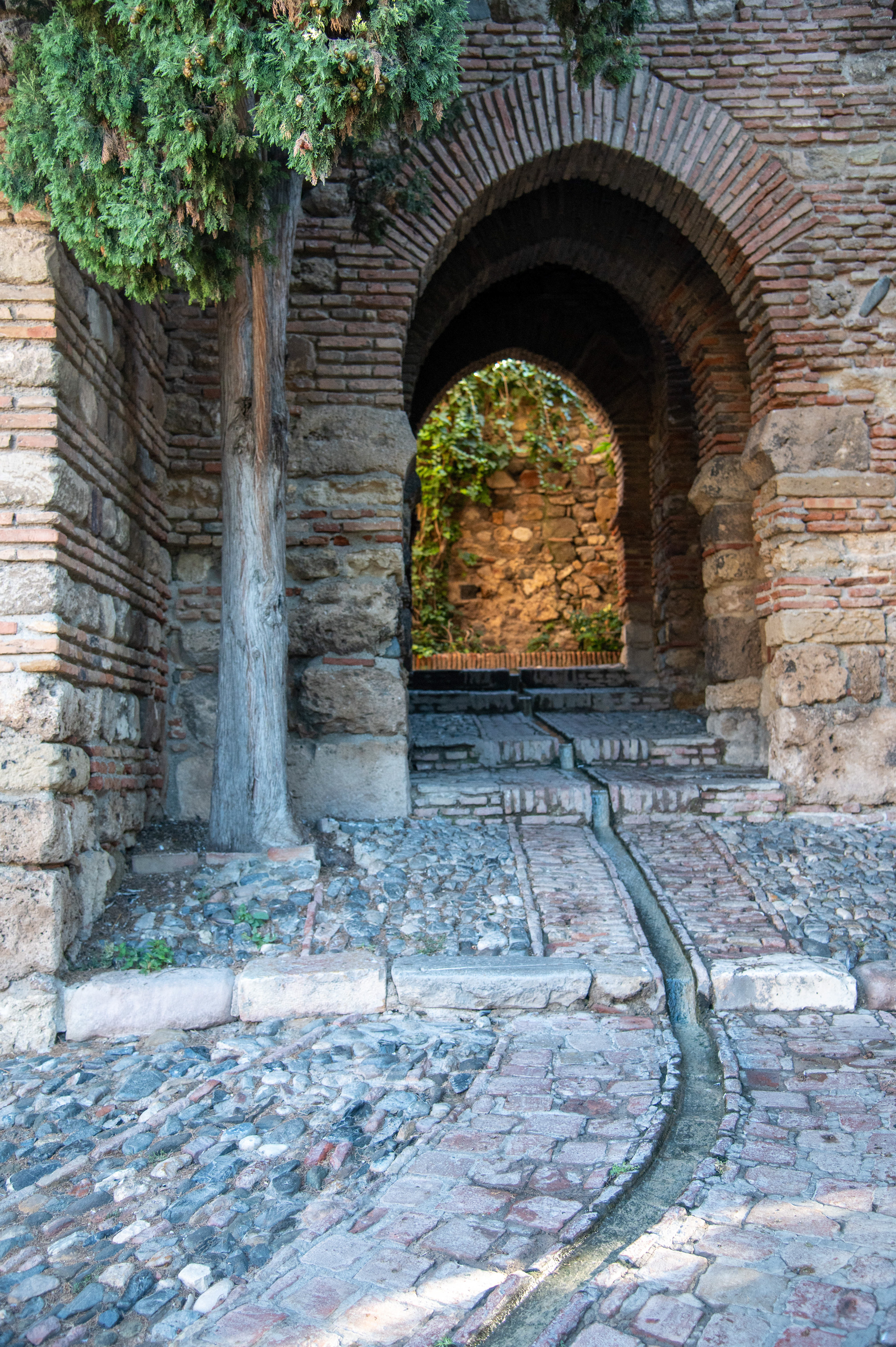 stone pathway leading through a series of brick arches