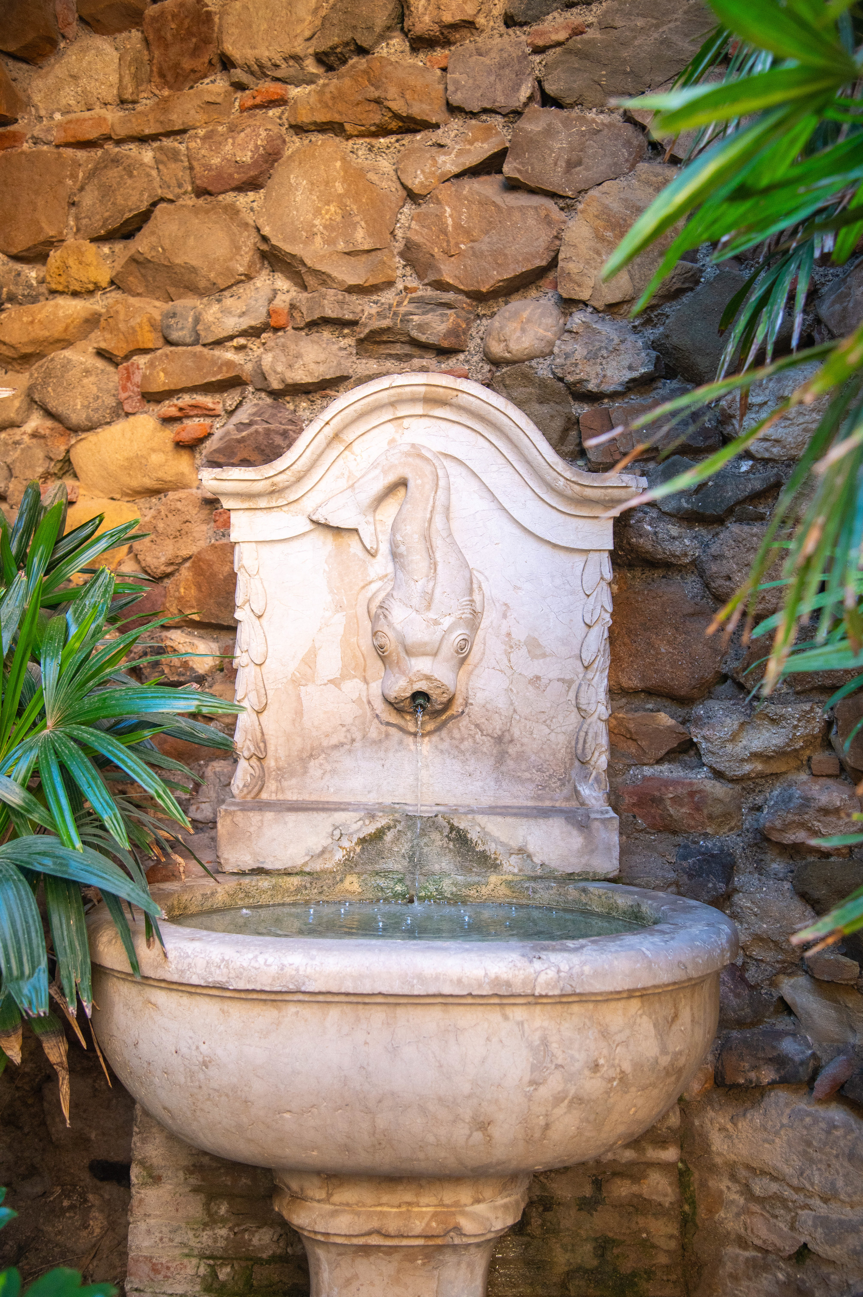 a stone fountain with a sculpted mask