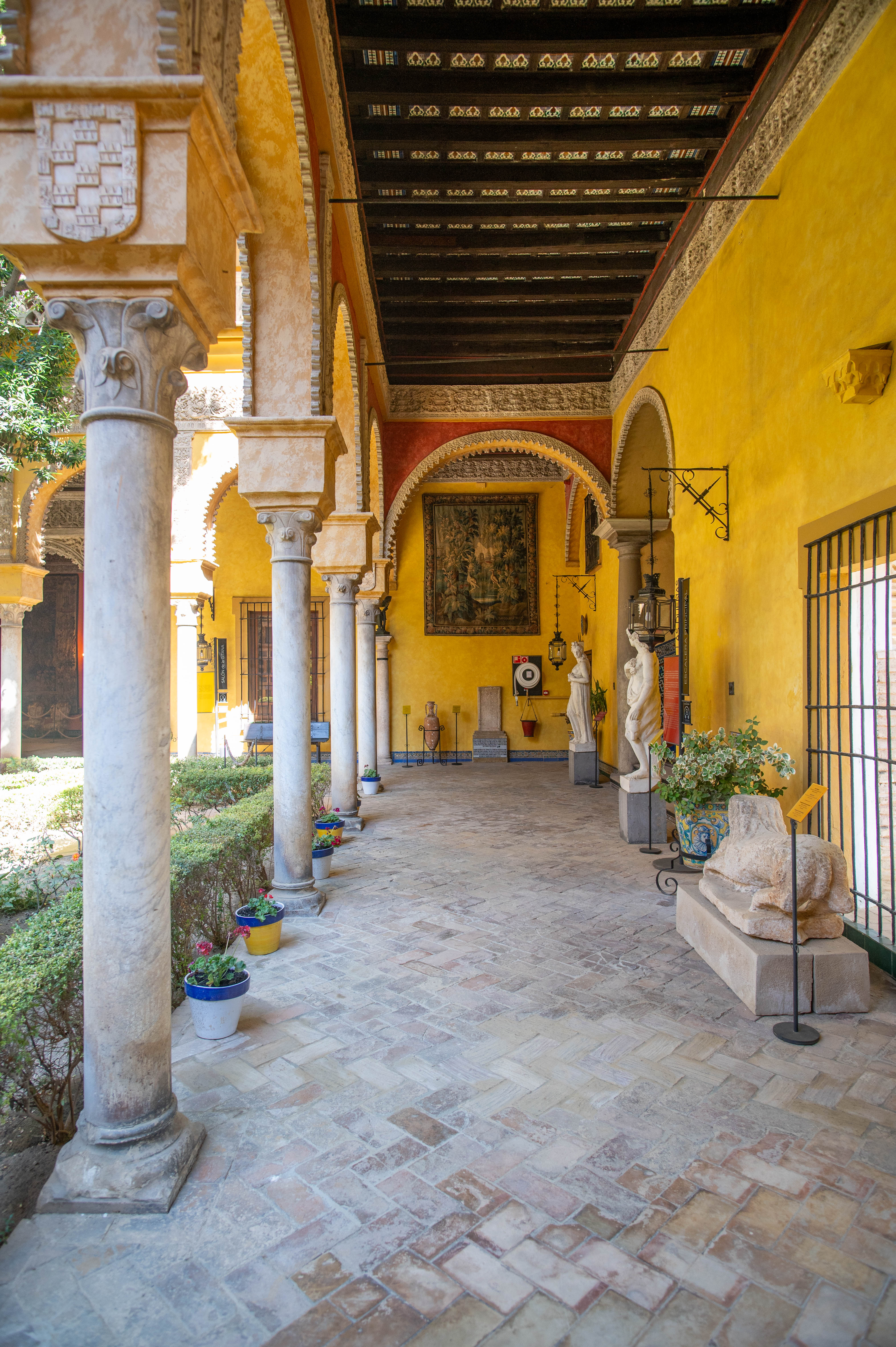 courtyard with architectural elements such as columns and arches, adorned with statues, potted plants