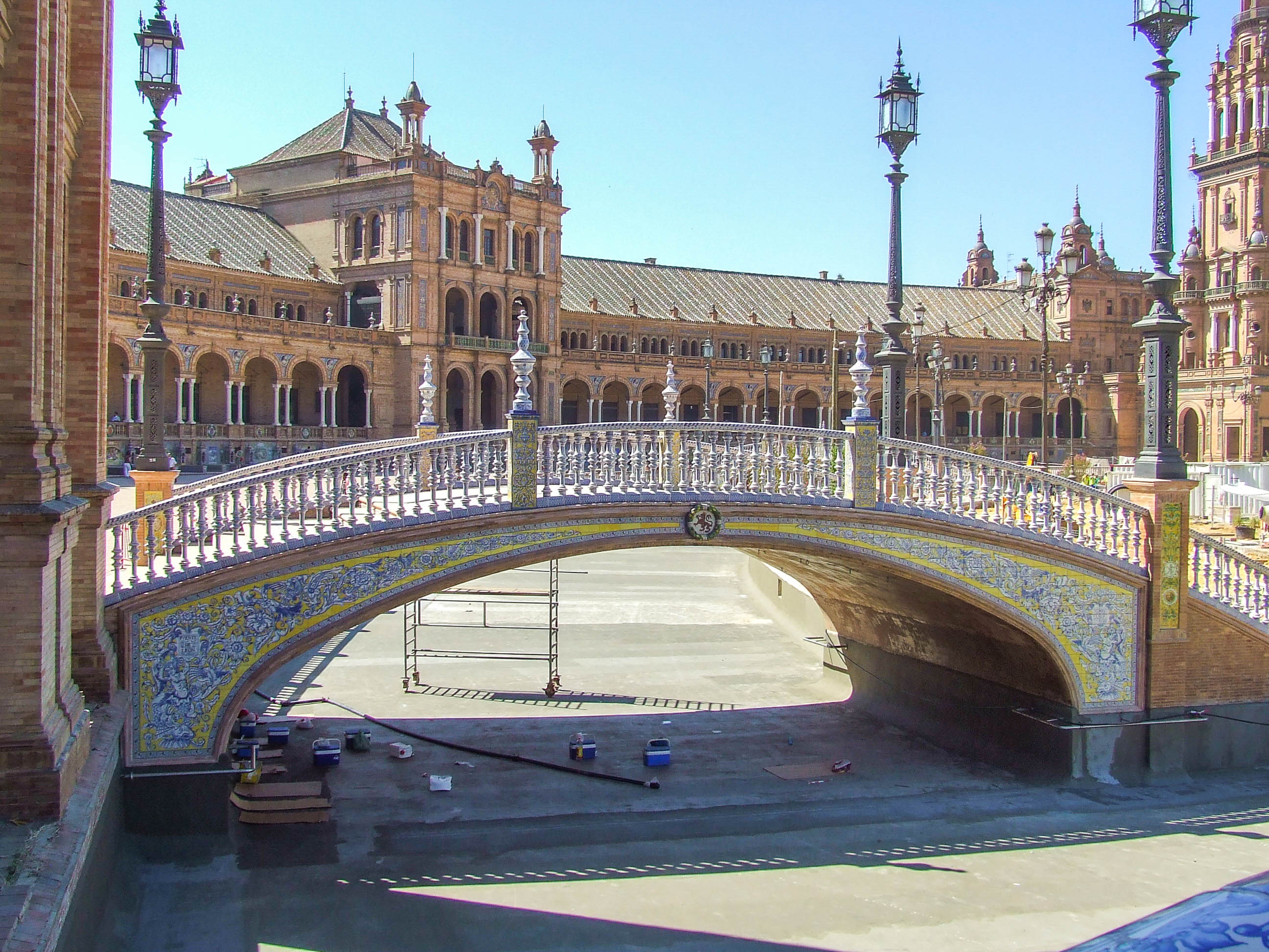 bridge with ornate railings and colorful tiles, spanning over a shallow fountain