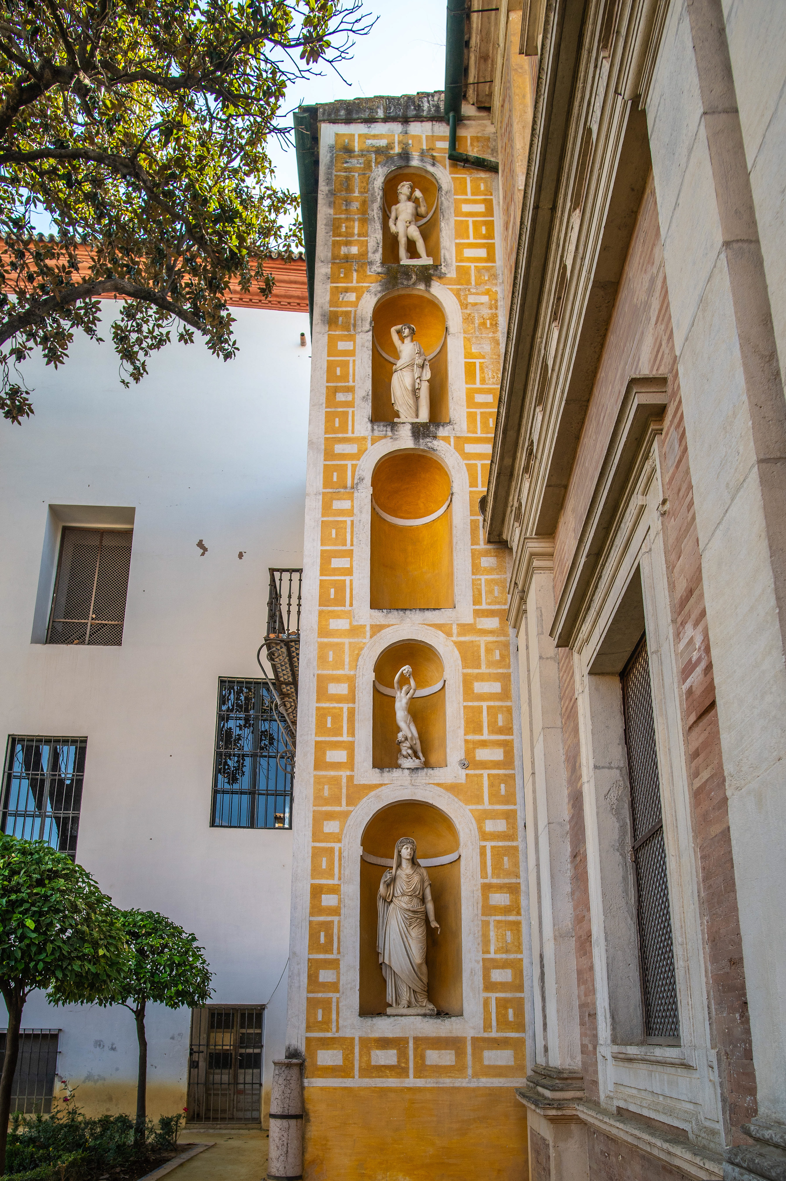 four niches, each containing a statue of a classical figure