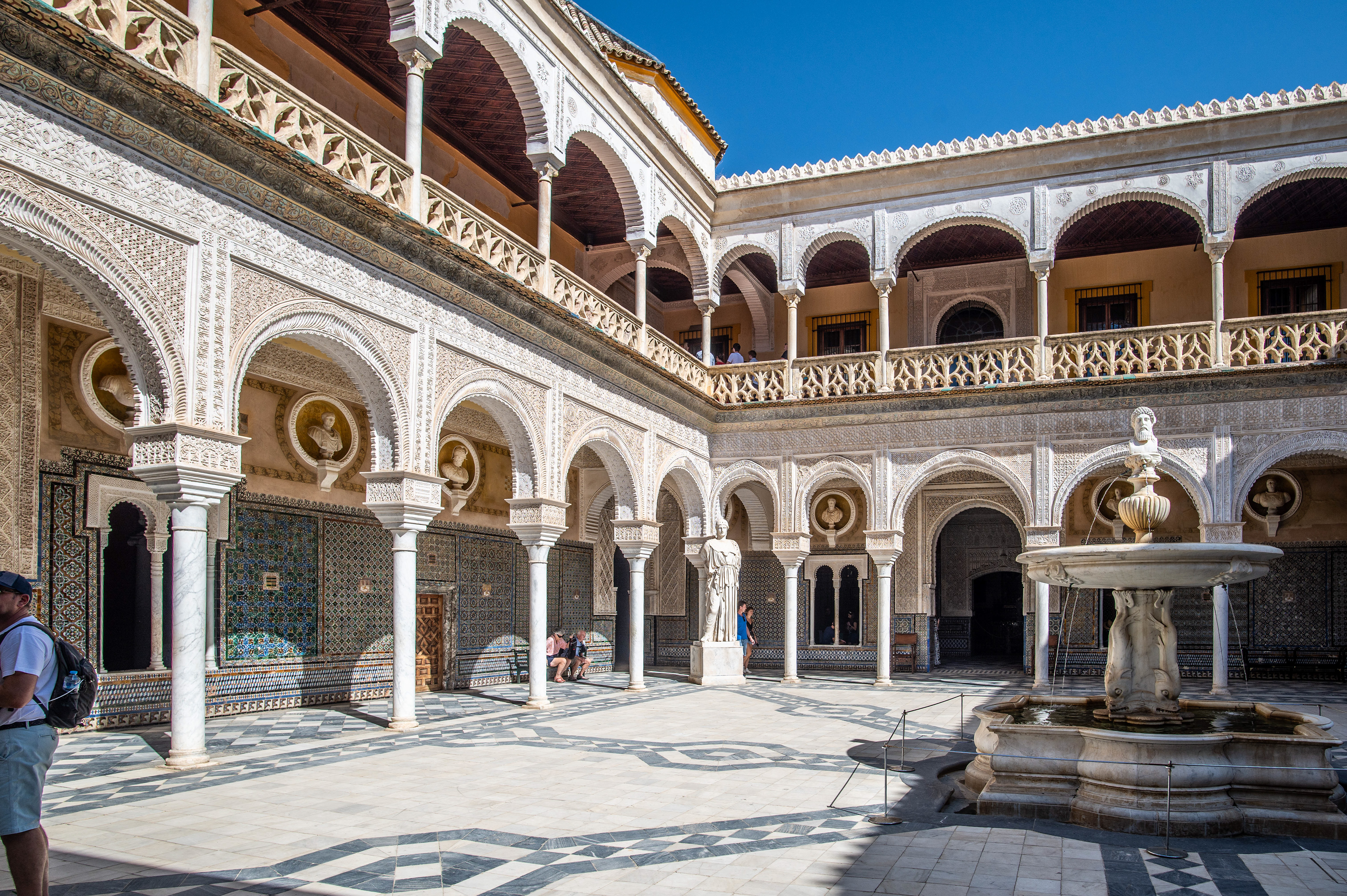 The courtyard features a central fountain and statues