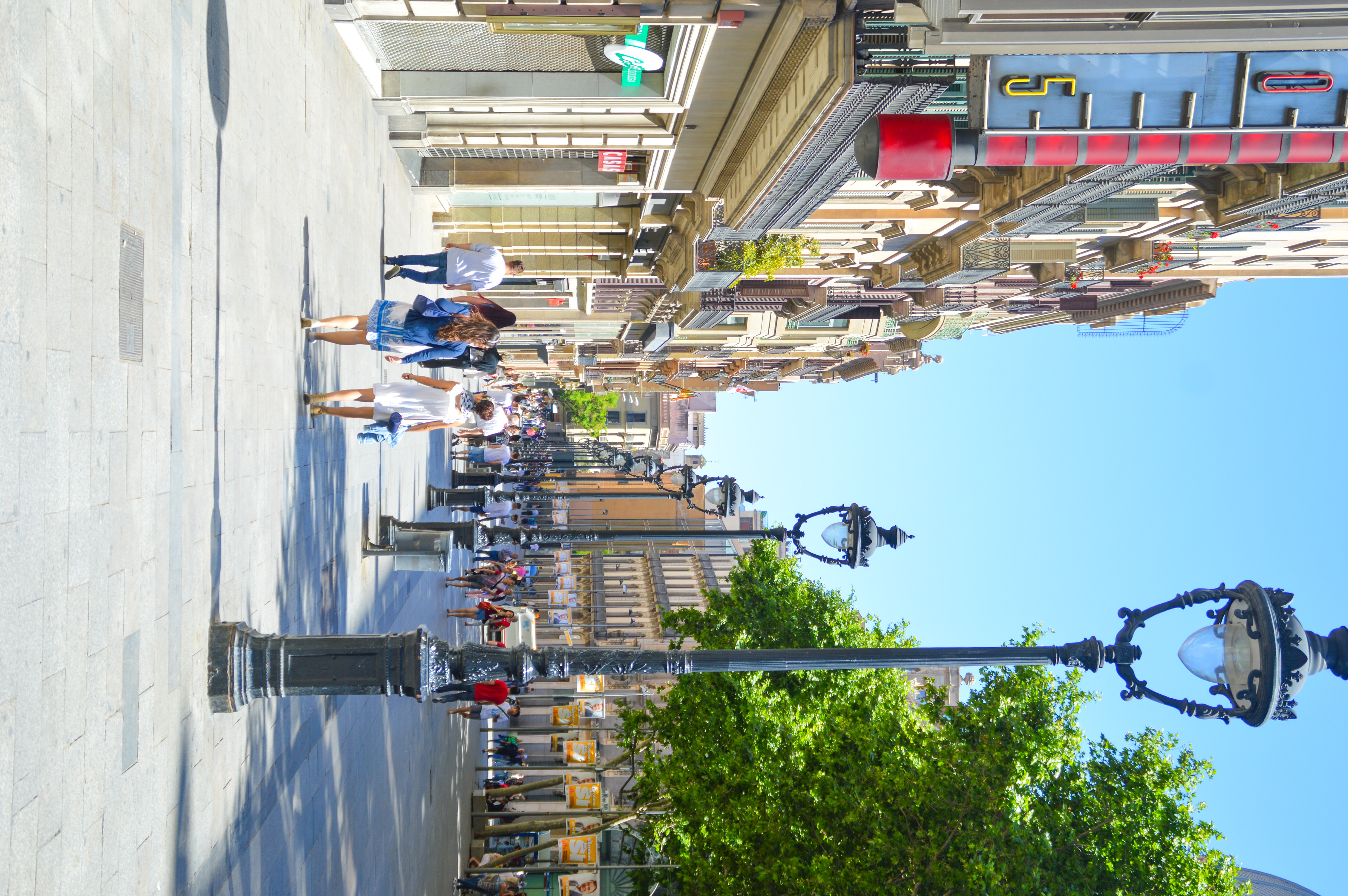 people walking along a pedestrian-only area lined with shops and outdoor seating