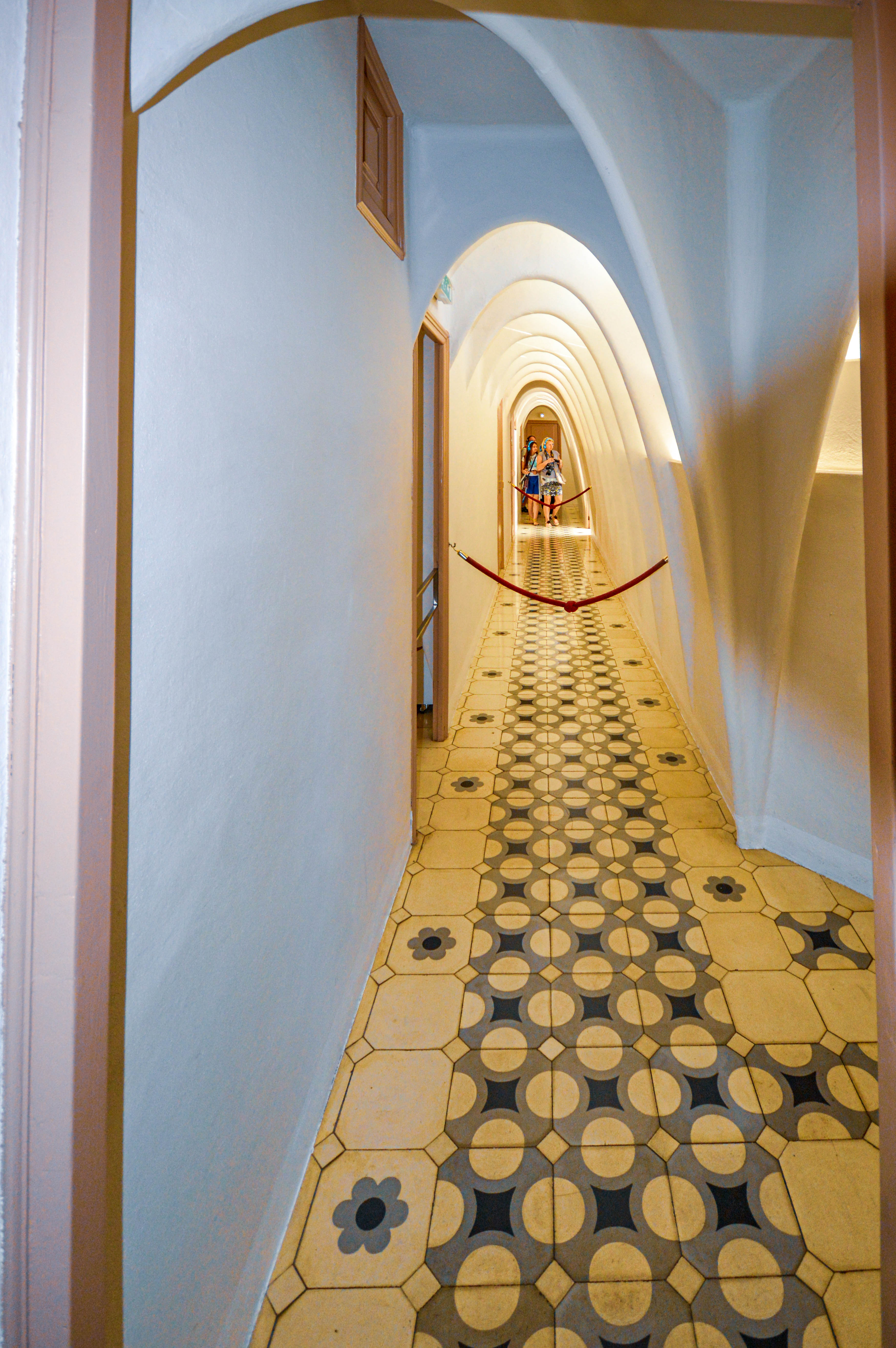 a long, narrow hallway with a patterned tiled floor and arched ceilings